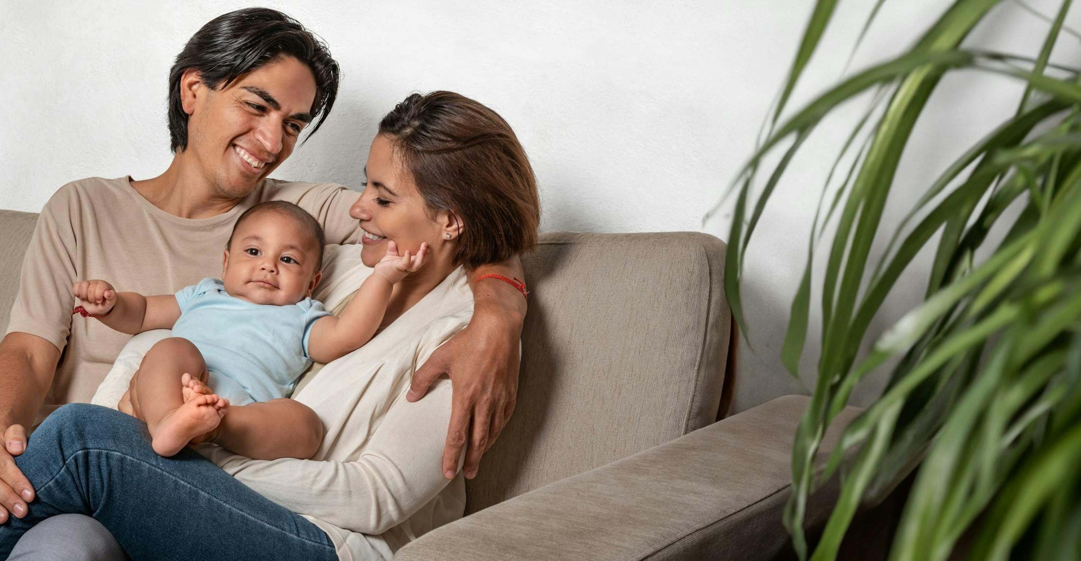 Couple on a couch smiling at their baby