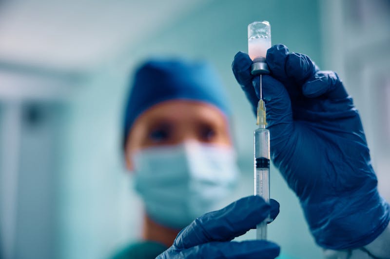 lose up of anesthesiologist preparing a syringe during a surgery in the hospital.