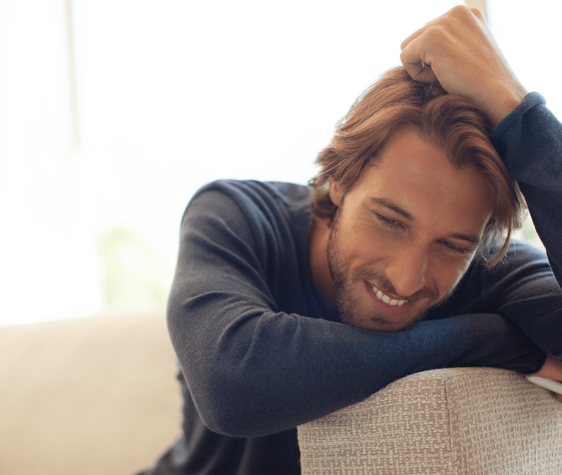 smiling man leaning on the arm of a couch