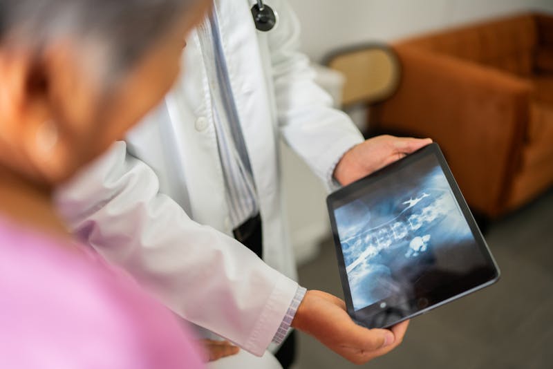 Close-up of doctor showing x-ray on tablet to patient during consultation at hospital