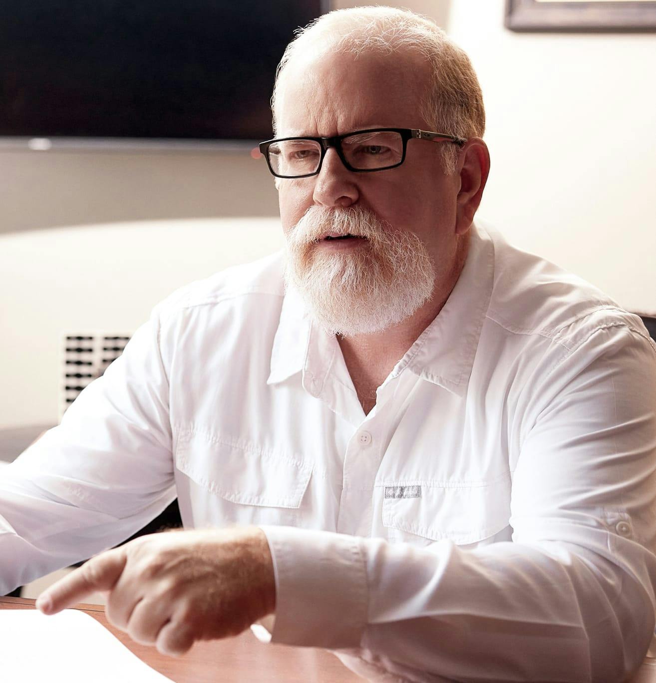 Man pointing to a paper document and speaking to someone