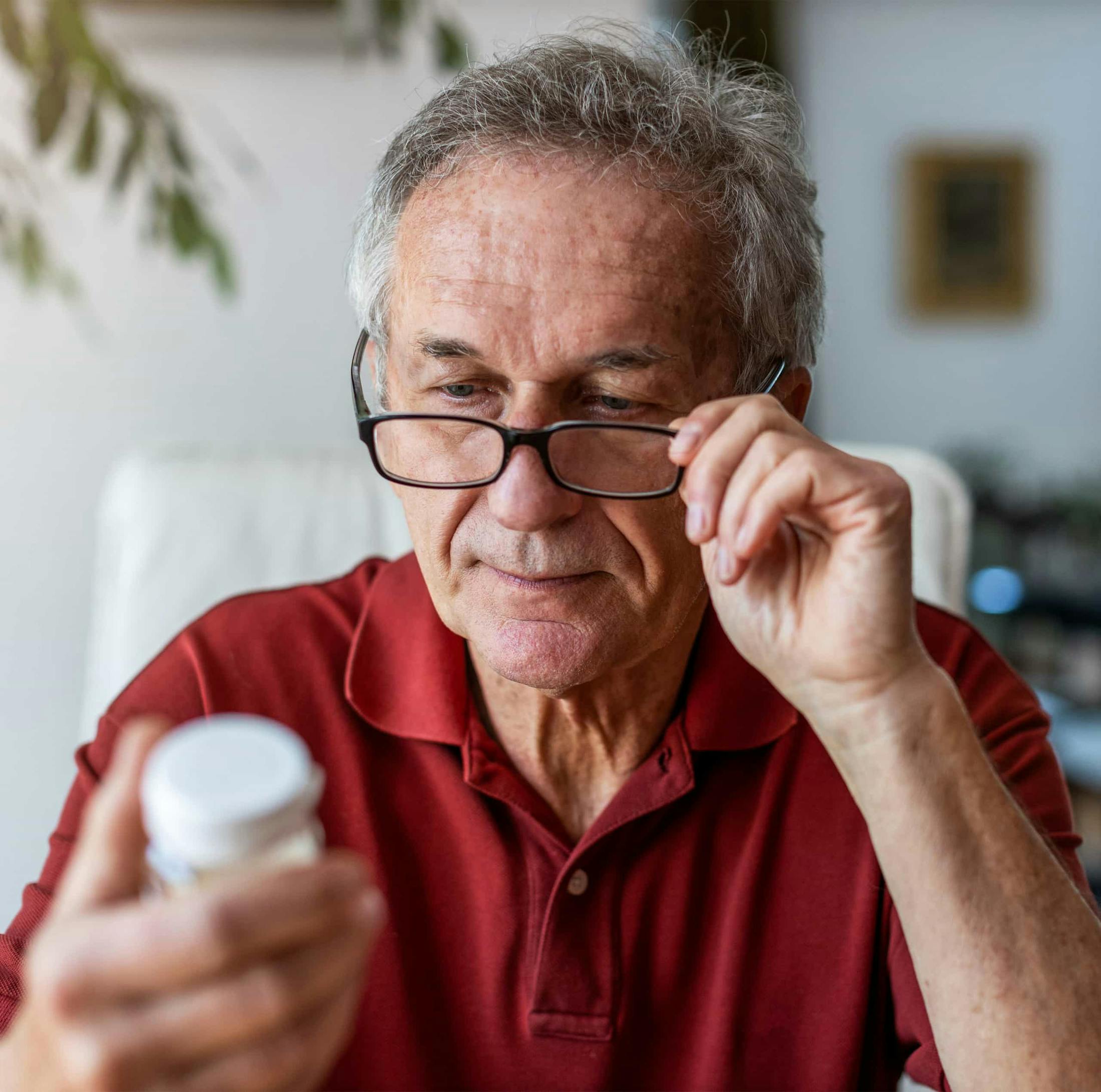 An older man looking at a pill bottle