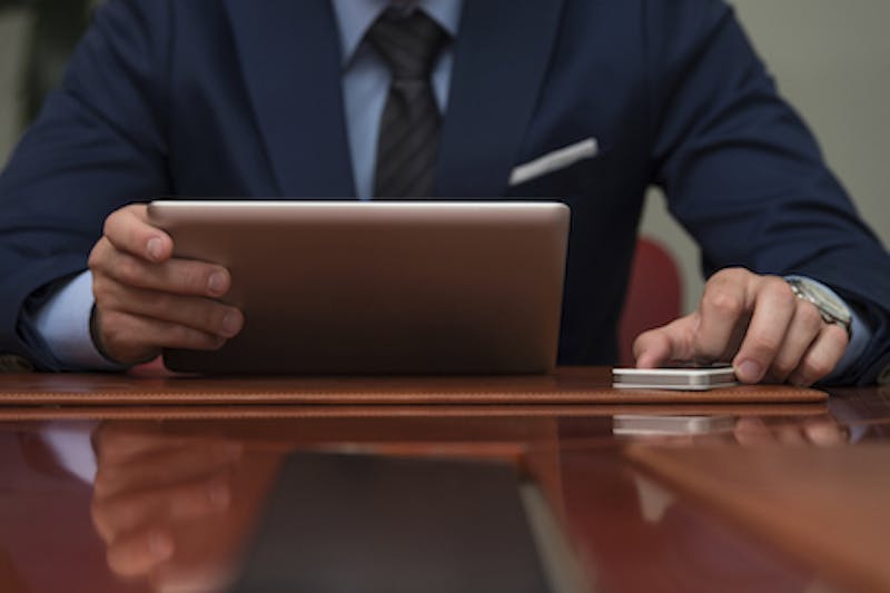 Close-up of a man in a suit holding a tablet