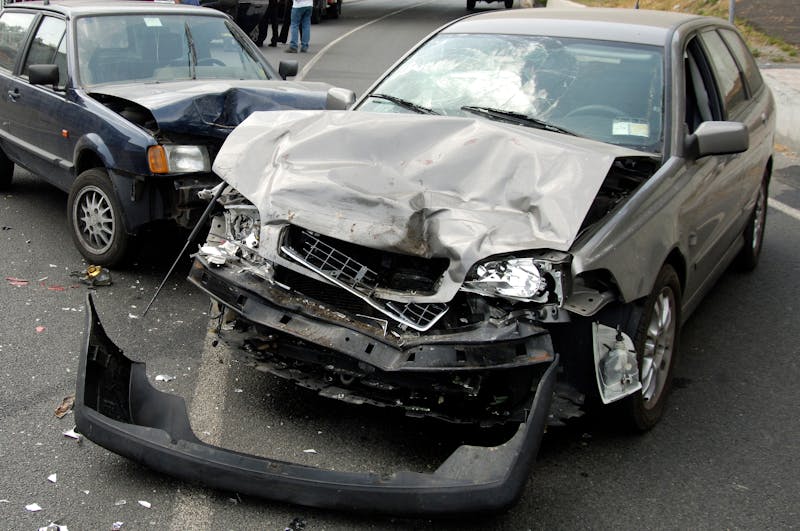 Two cars have been in a collison and both front ends of the cars are totaled from hitting into each other.