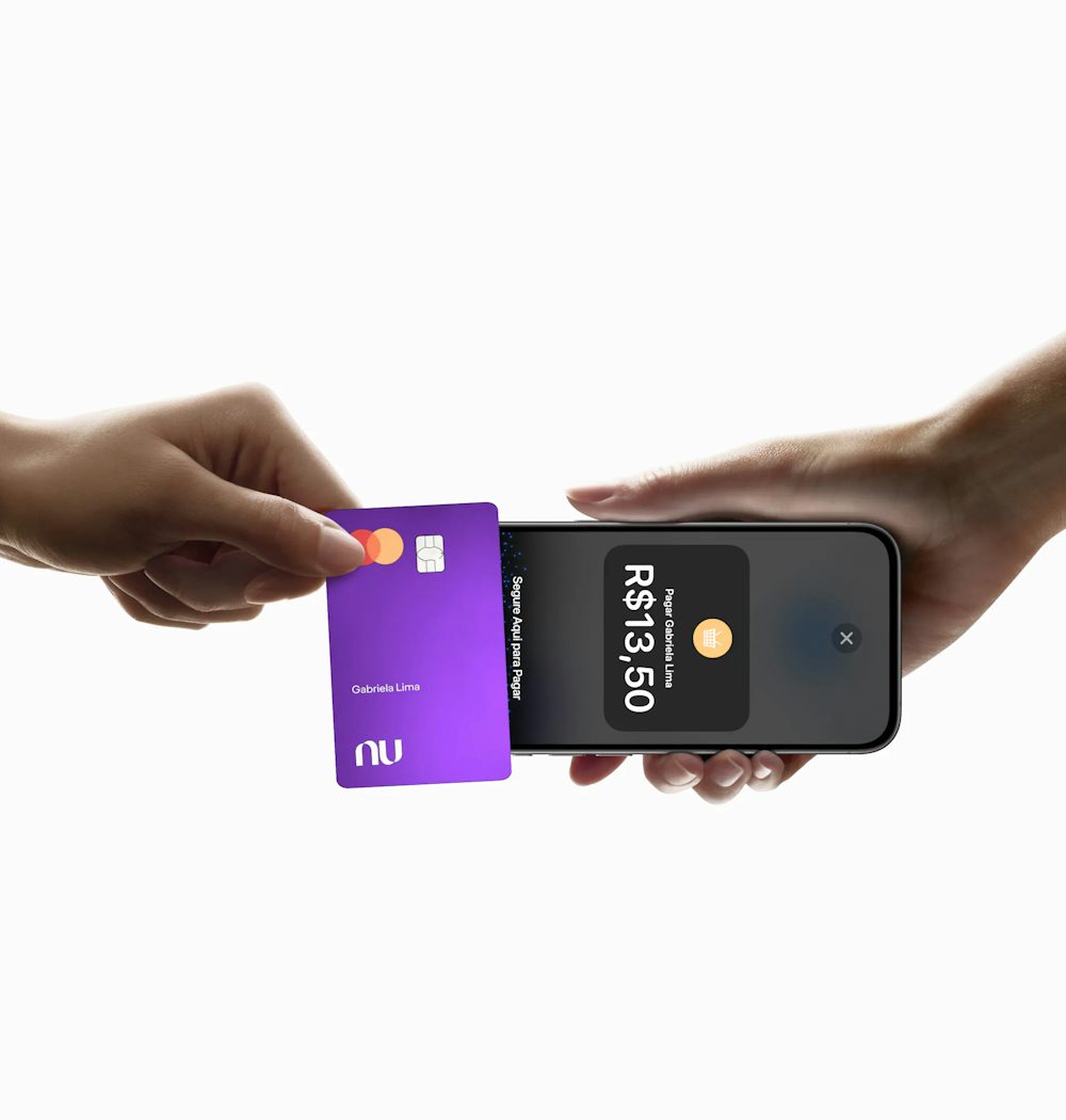 Em vista lateral, cartão Nubank é utilizado para pagamento por aproximação em um celular, que indica na tela a confirmação do pagamento.