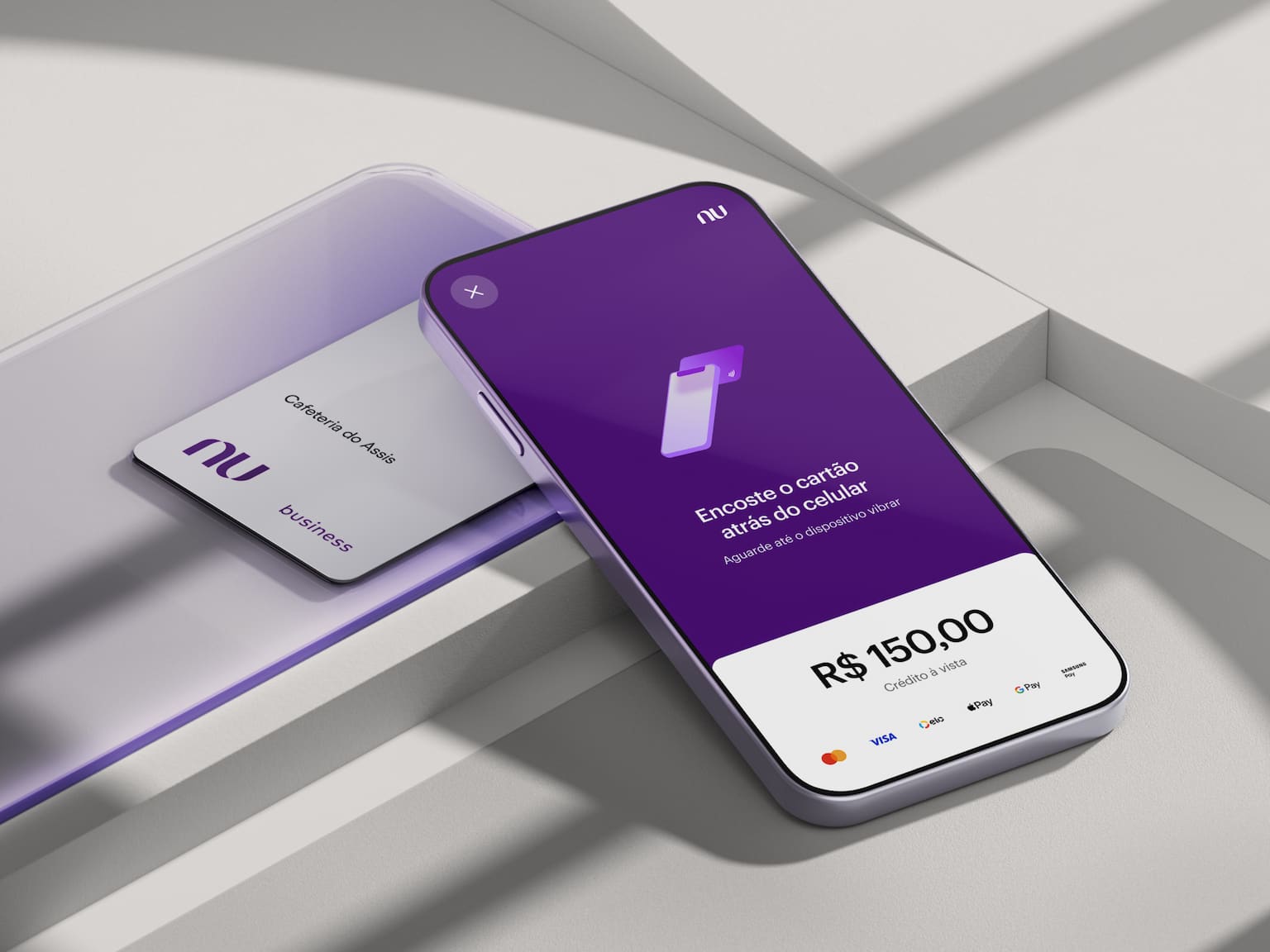 Celular com aplicativo Nubank aberto na tela ao lado de um cartão de crédito PJ. O celular e o cartão estão apoiados em uma forma geométrica.