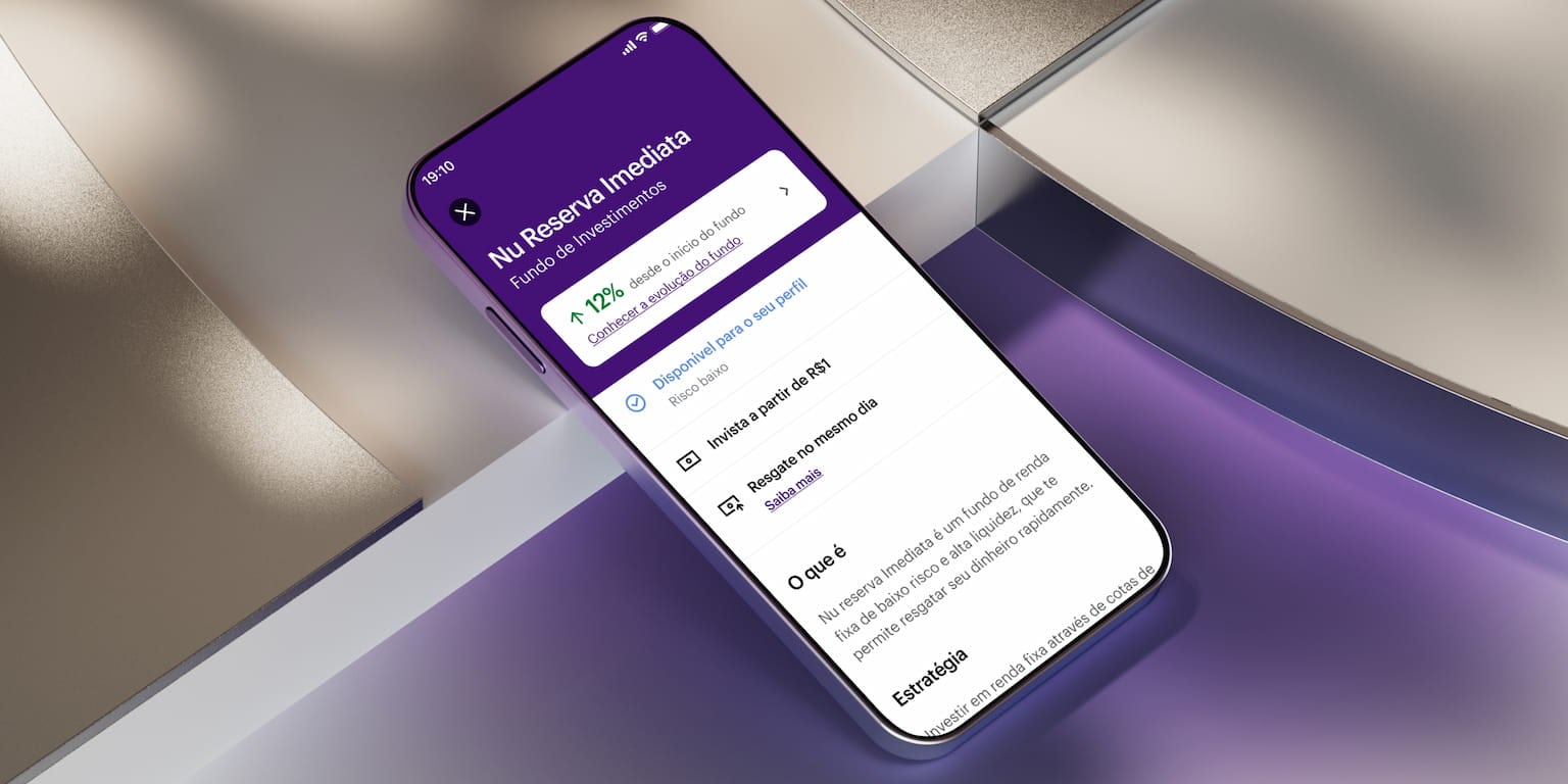 Apoiado sobre uma plataforma metalizada iluminada por uma luz roxa há um smartphone na tela do fundo de investimento Nu Reserva Imediata