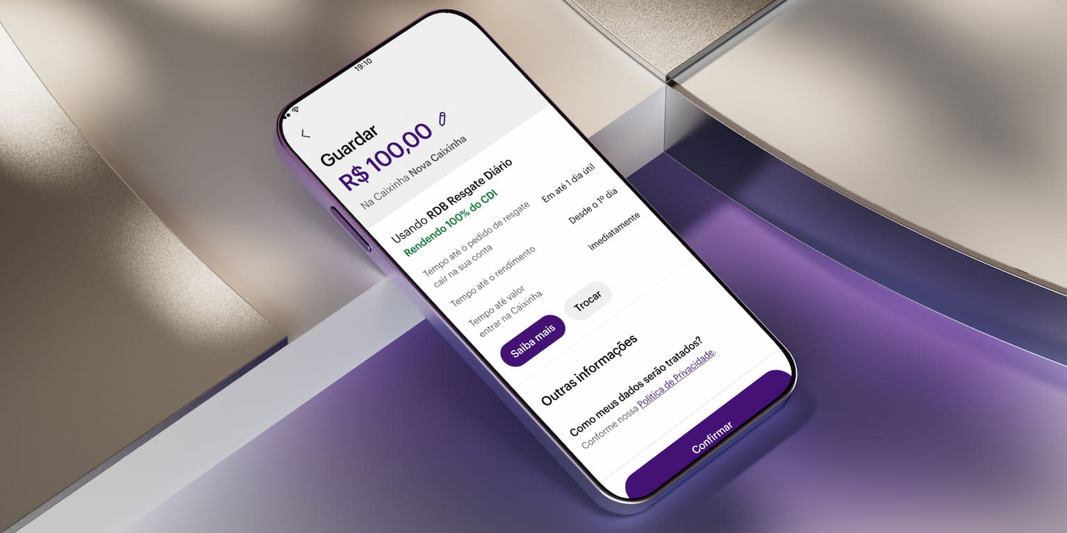 Celular apoiado em uma forma geométrica branca com aplicativo Nubank aberto na área de Caixinhas, guardando 100 reais em uma nova caixinha.
