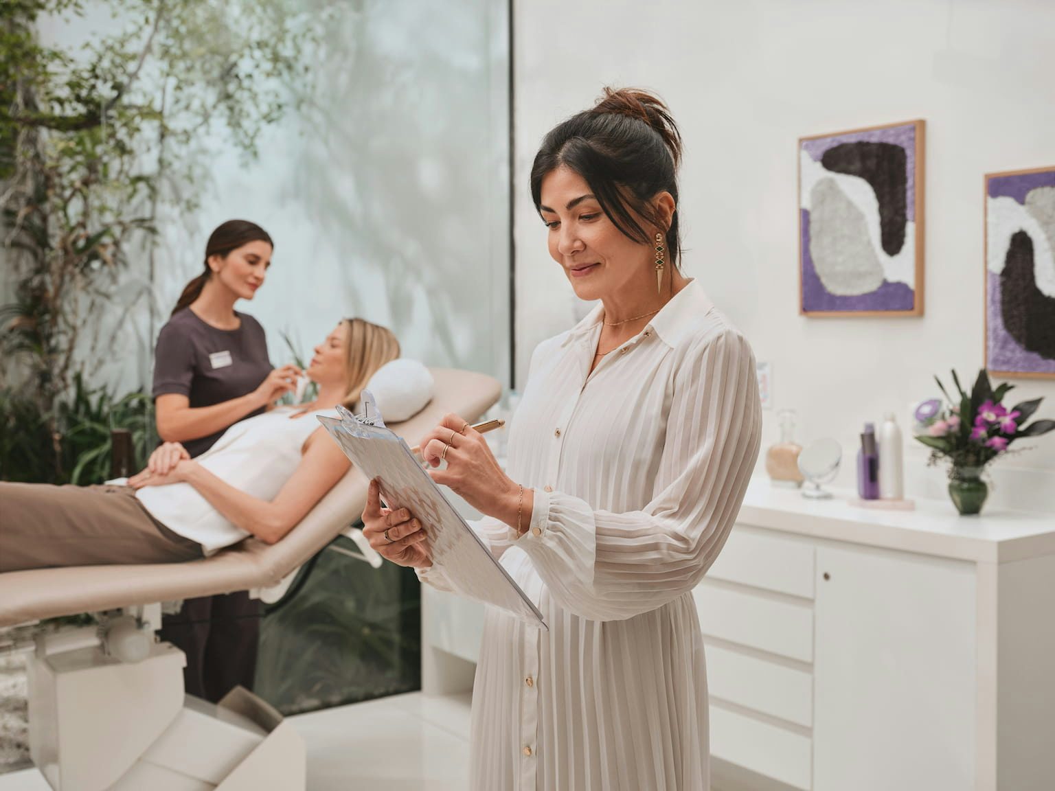 Mulher usando um vestido branco escreve em uma prancheta