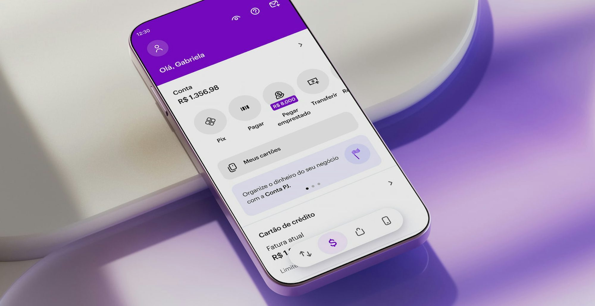 Celular apoiado em uma forma geométrica branca com aplicativo Nubank aberto na tela inicial.