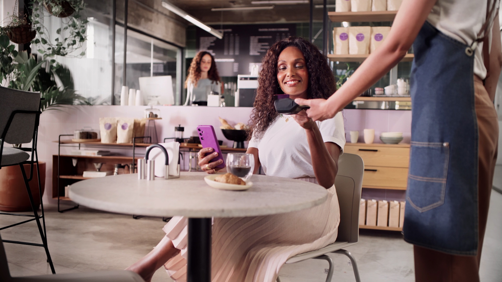 Mulher em cafeteria pagando com o cartão Nubank