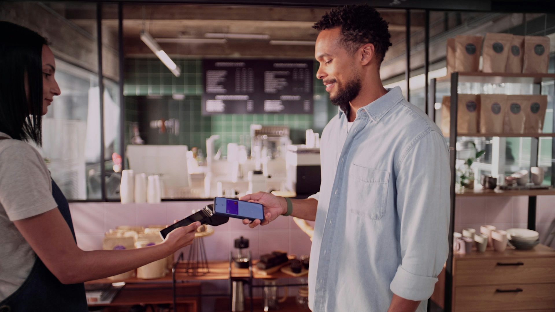 Homem em uma cafeteria pagando com o cartão Nubank