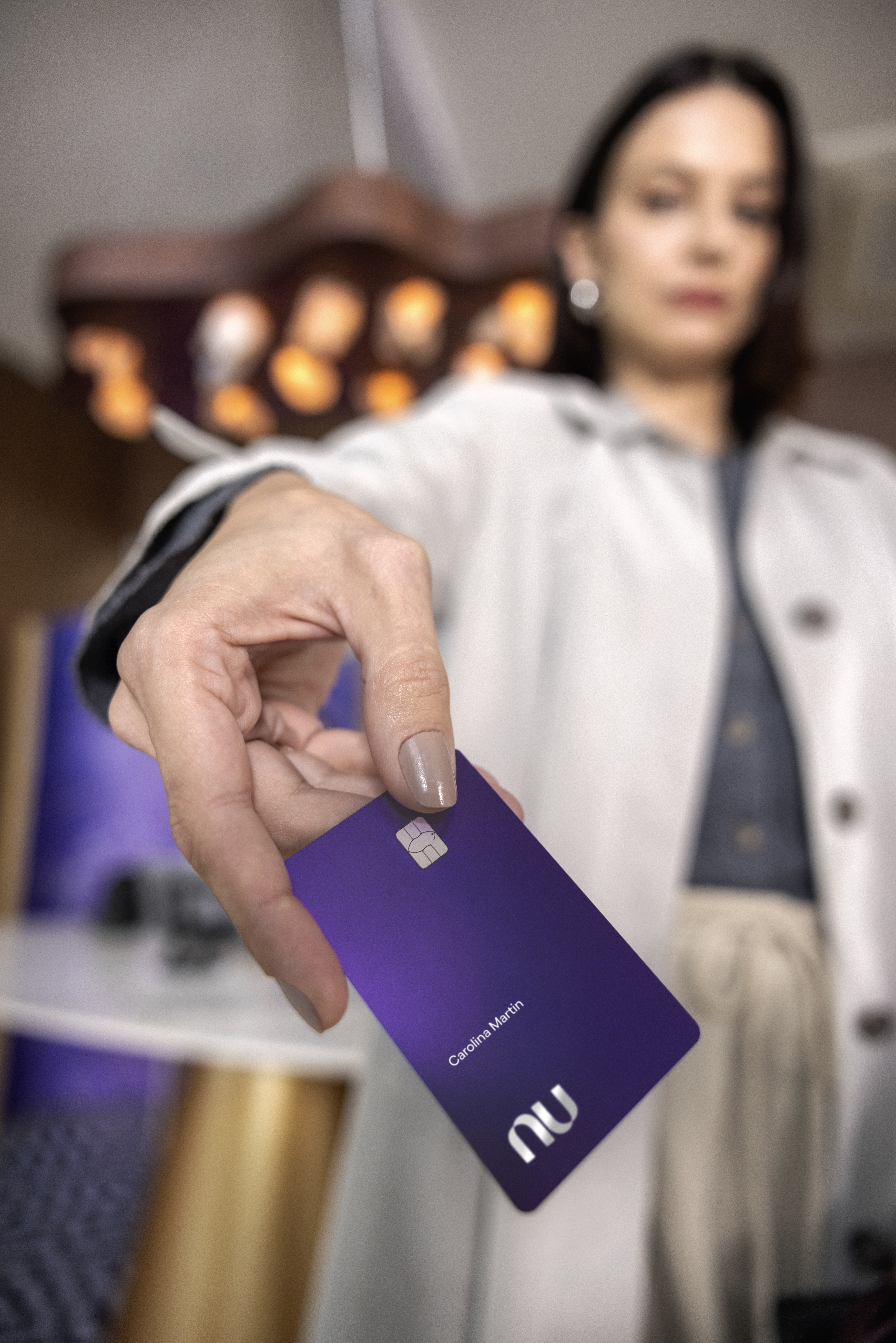 Mulher branca na entrada em uma sala vip estendendo um cartão Ultravioleta