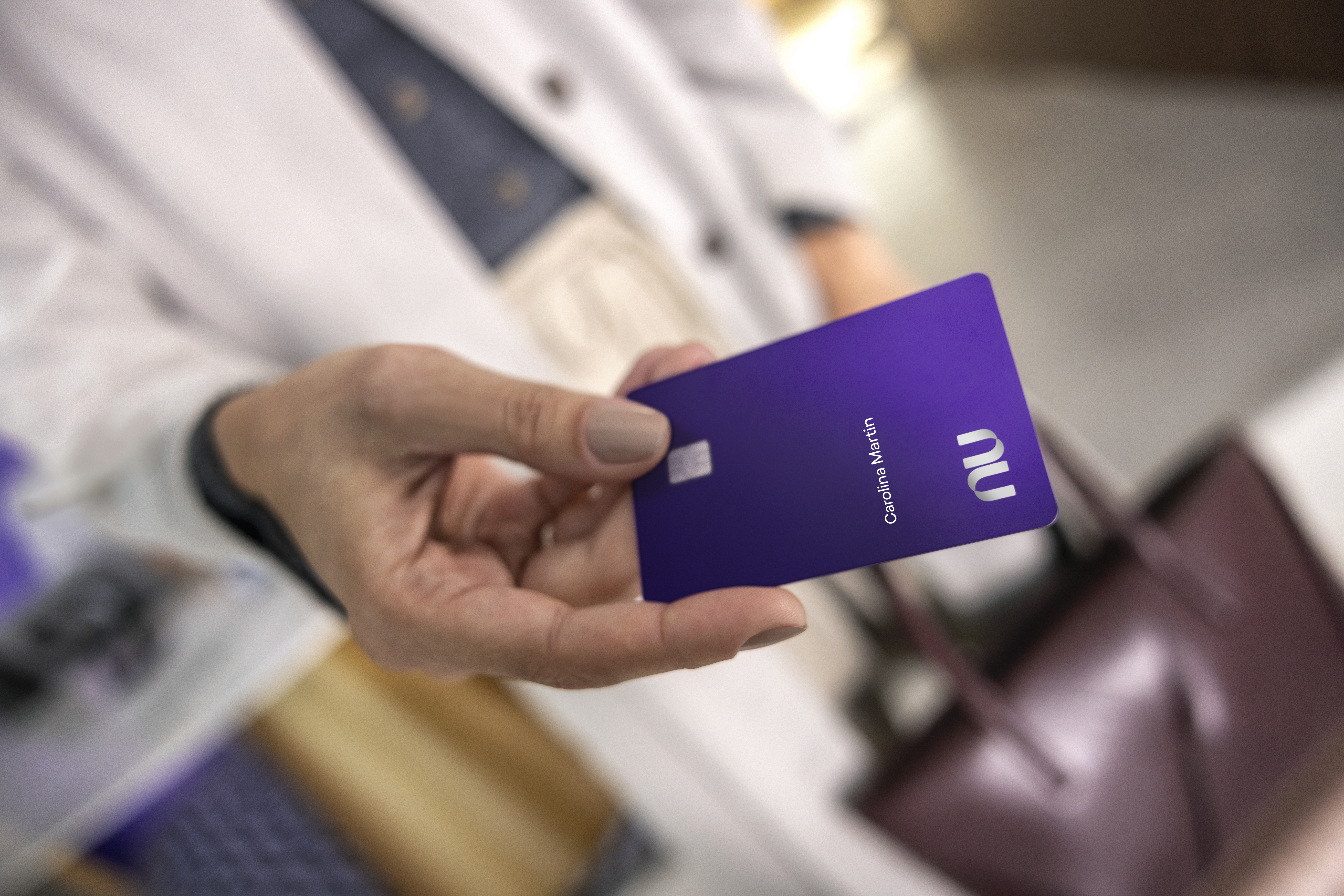 Mulher branca entregando um cartão ultravioleta, com foco em sua mão.