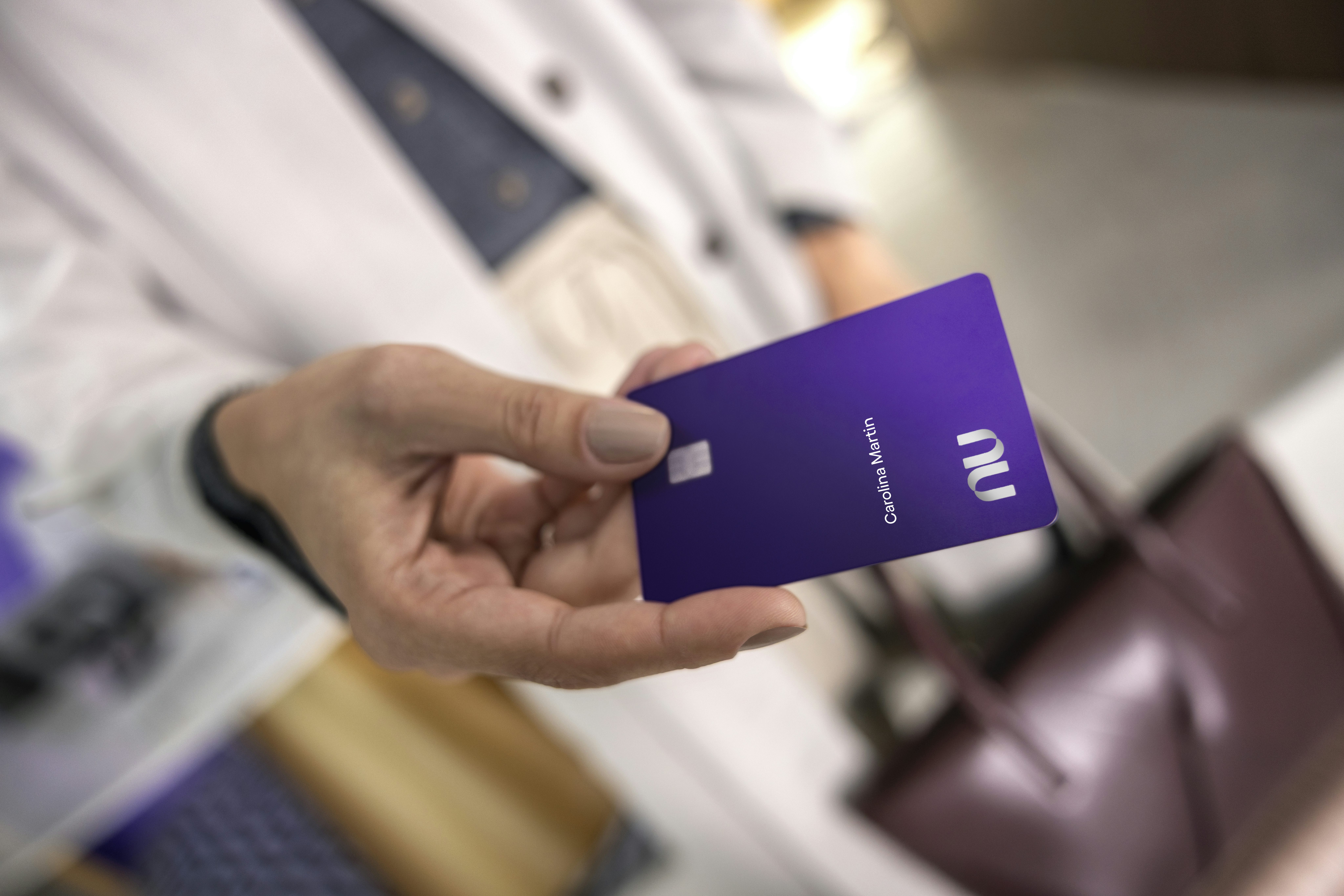 Mulher branca entregando um cartão ultravioleta, com foco em sua mão.