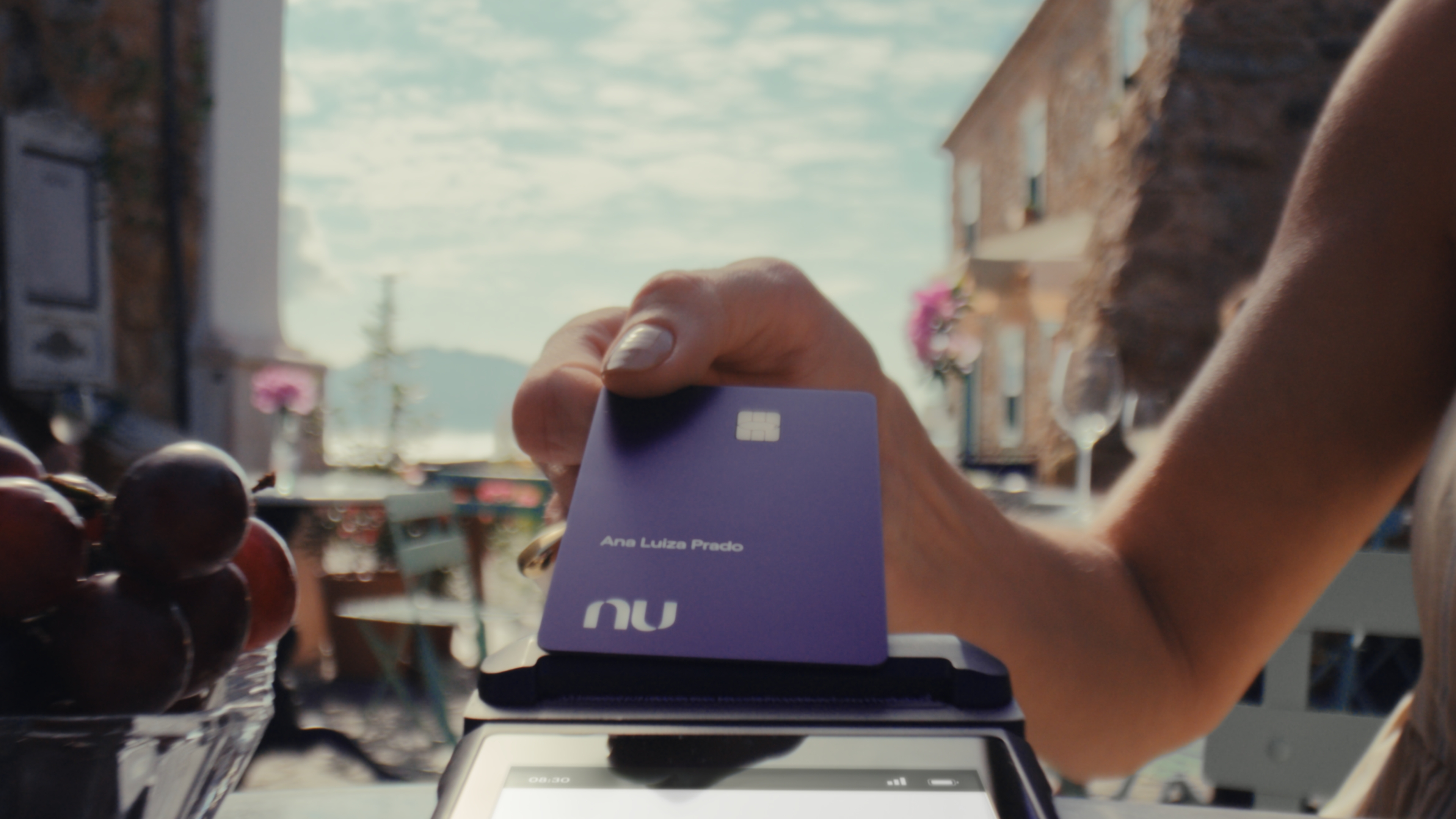 Cartão Ultravioleta sendo encostado em uma máquina de compras por uma mulher completando uma transação