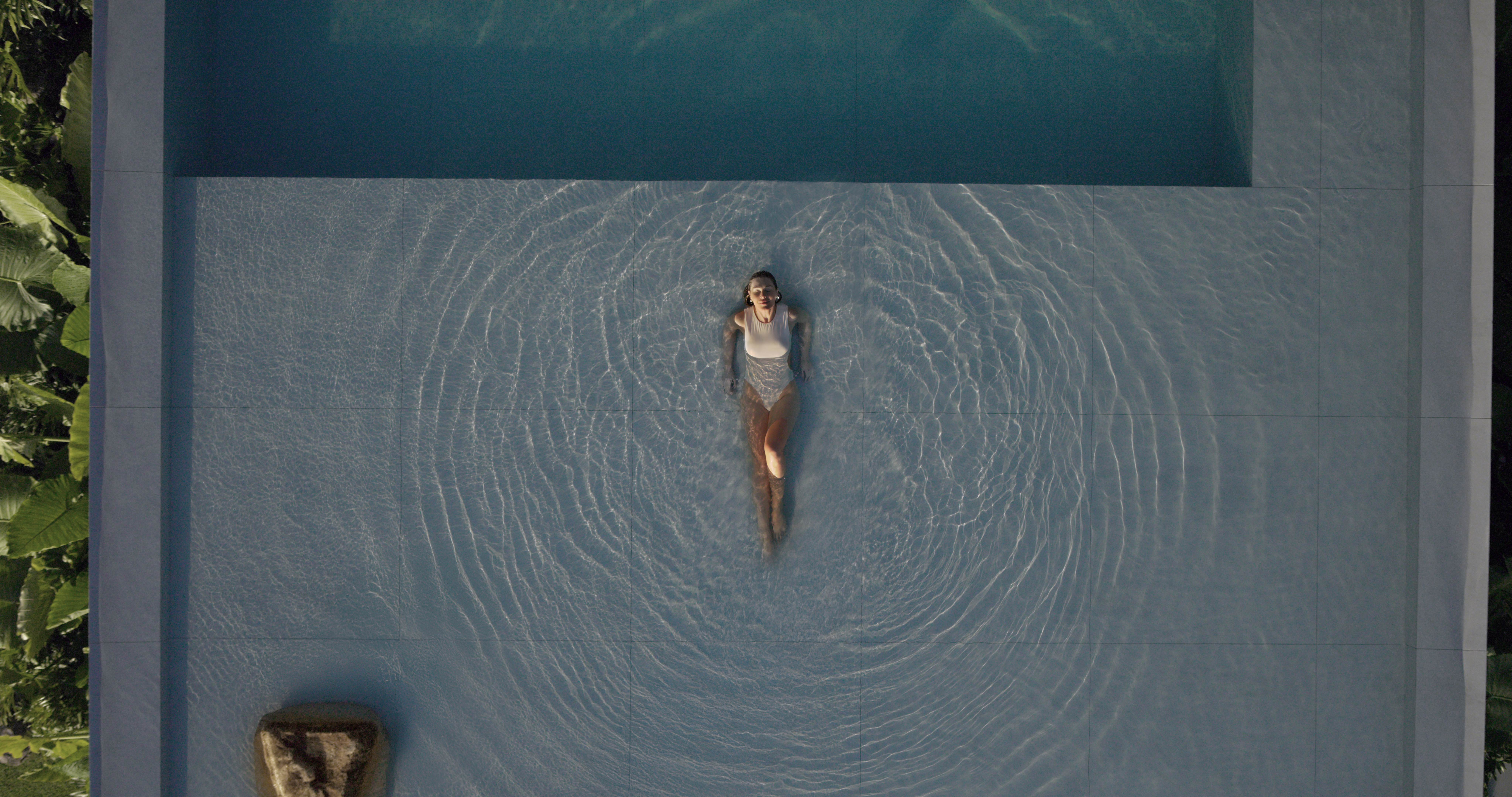 Uma mulher deitada em uma larga piscina curtindo seu momento de lazer