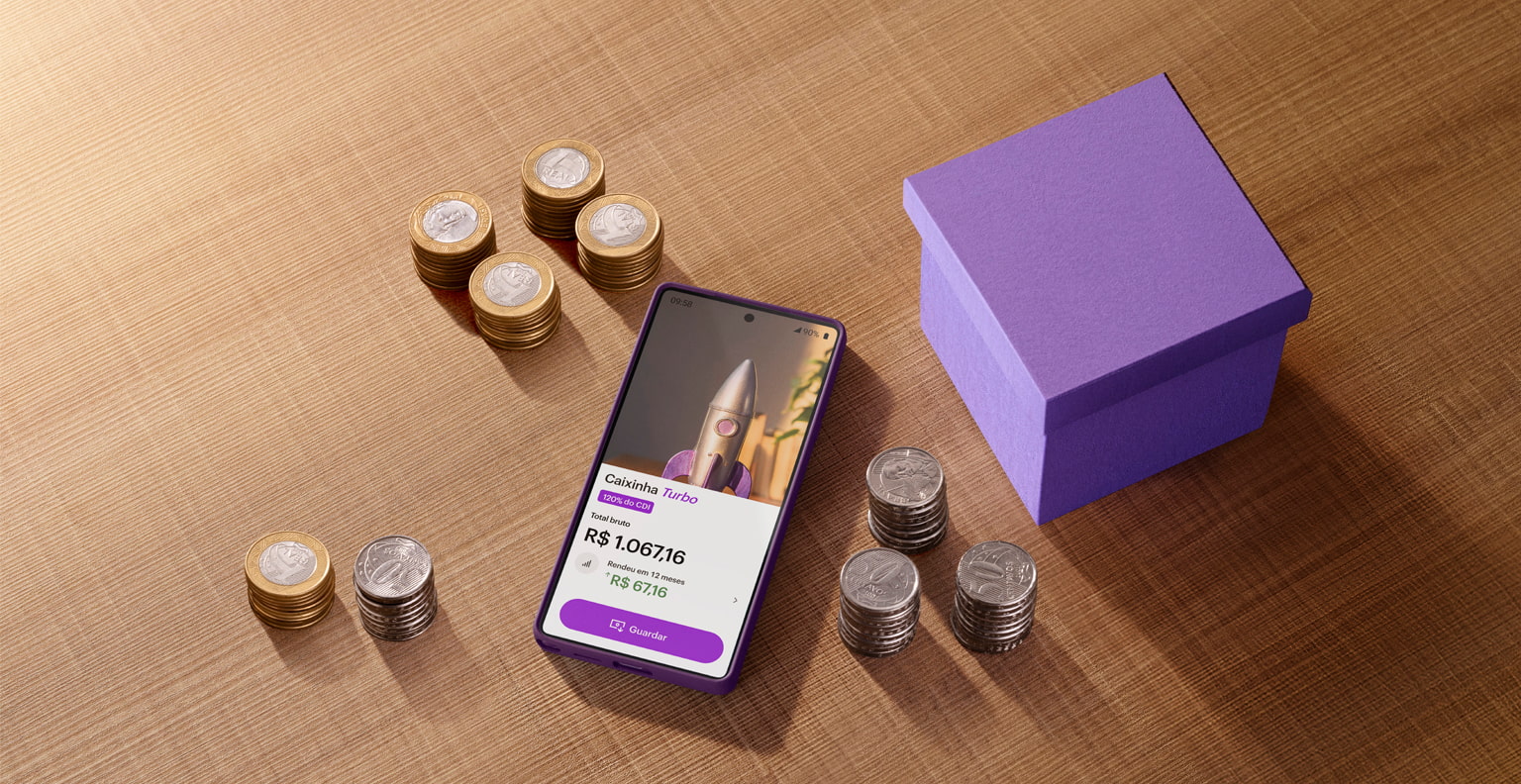 Smartphone com o app Nubank na tela, na área de Caixinha Turbo, sobre uma mesa ao lado de uma caixinha roxa e rodeado de moedas.