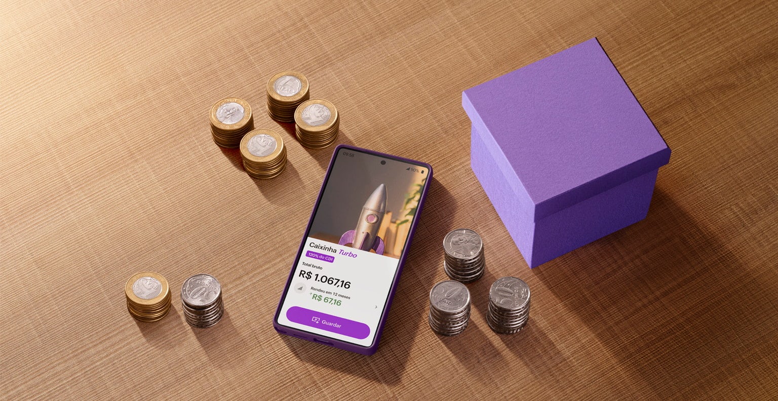 Smartphone com o app Nubank na tela, na área de Caixinha Turbo, sobre uma mesa ao lado de uma caixinha roxa e rodeado de moedas.