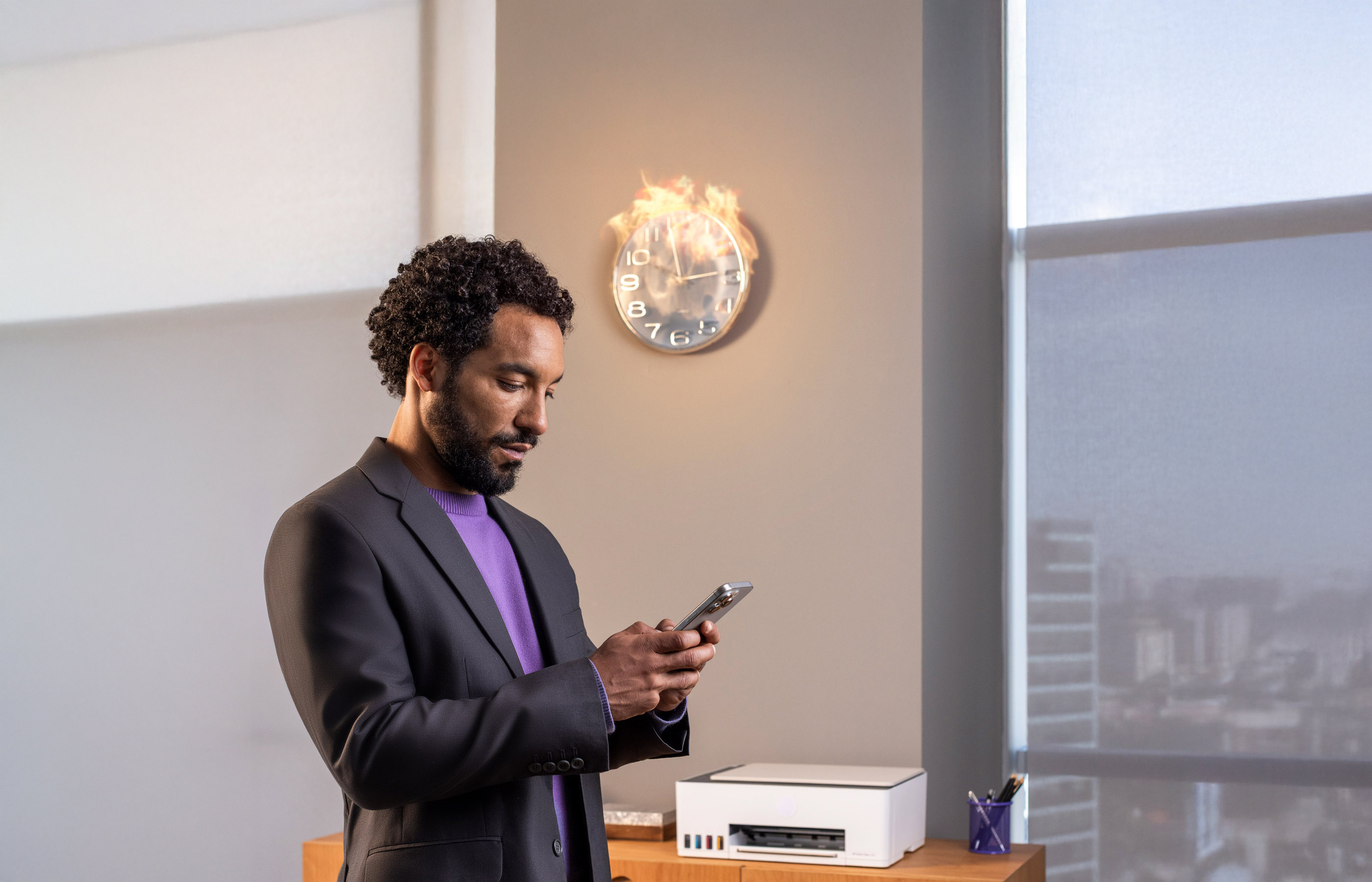 Empreendedor em pé mexendo no celular em escritório com relógio de parede em chamas