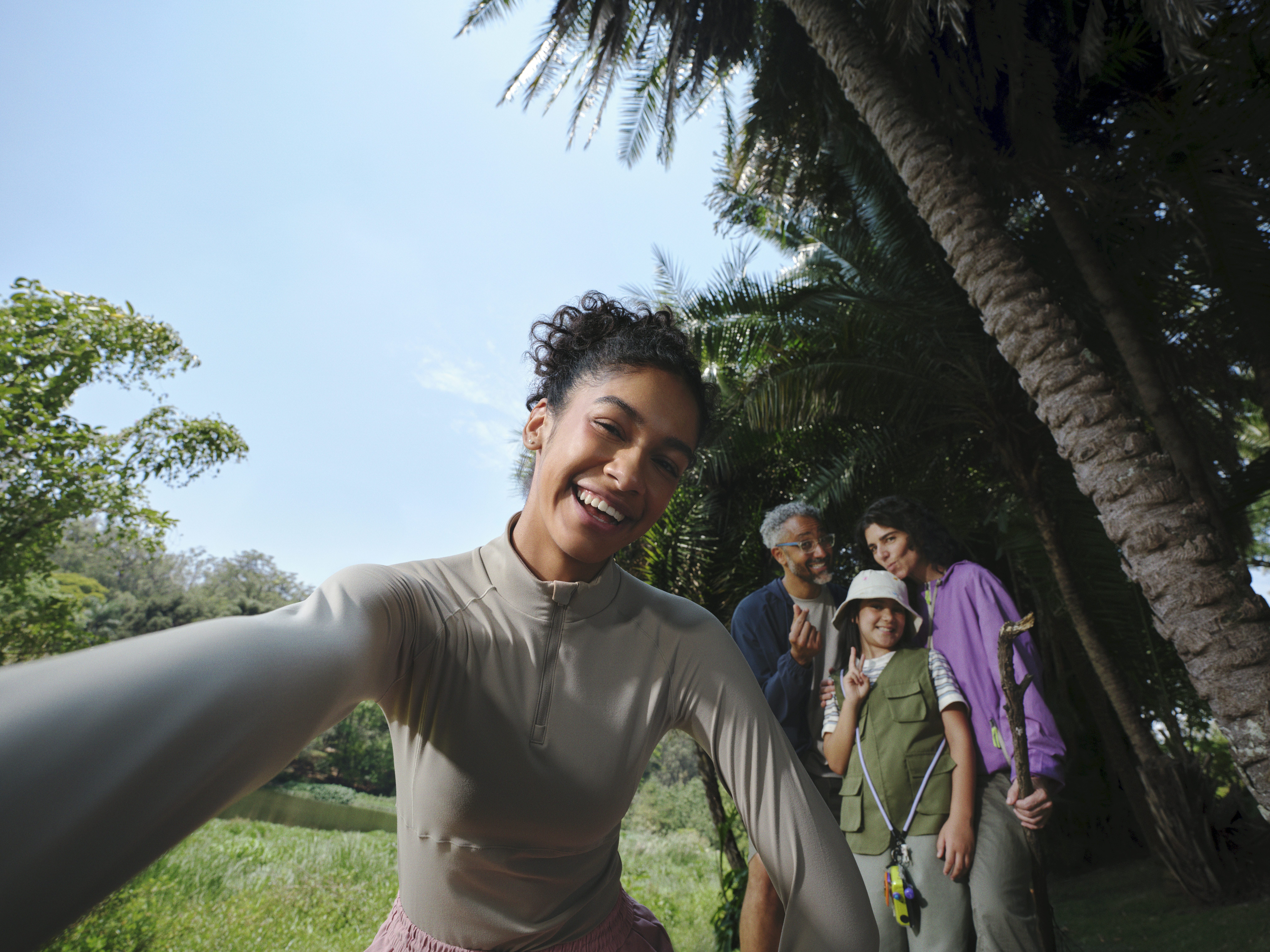 Mulher tira self com a família em meio as arvores no parque