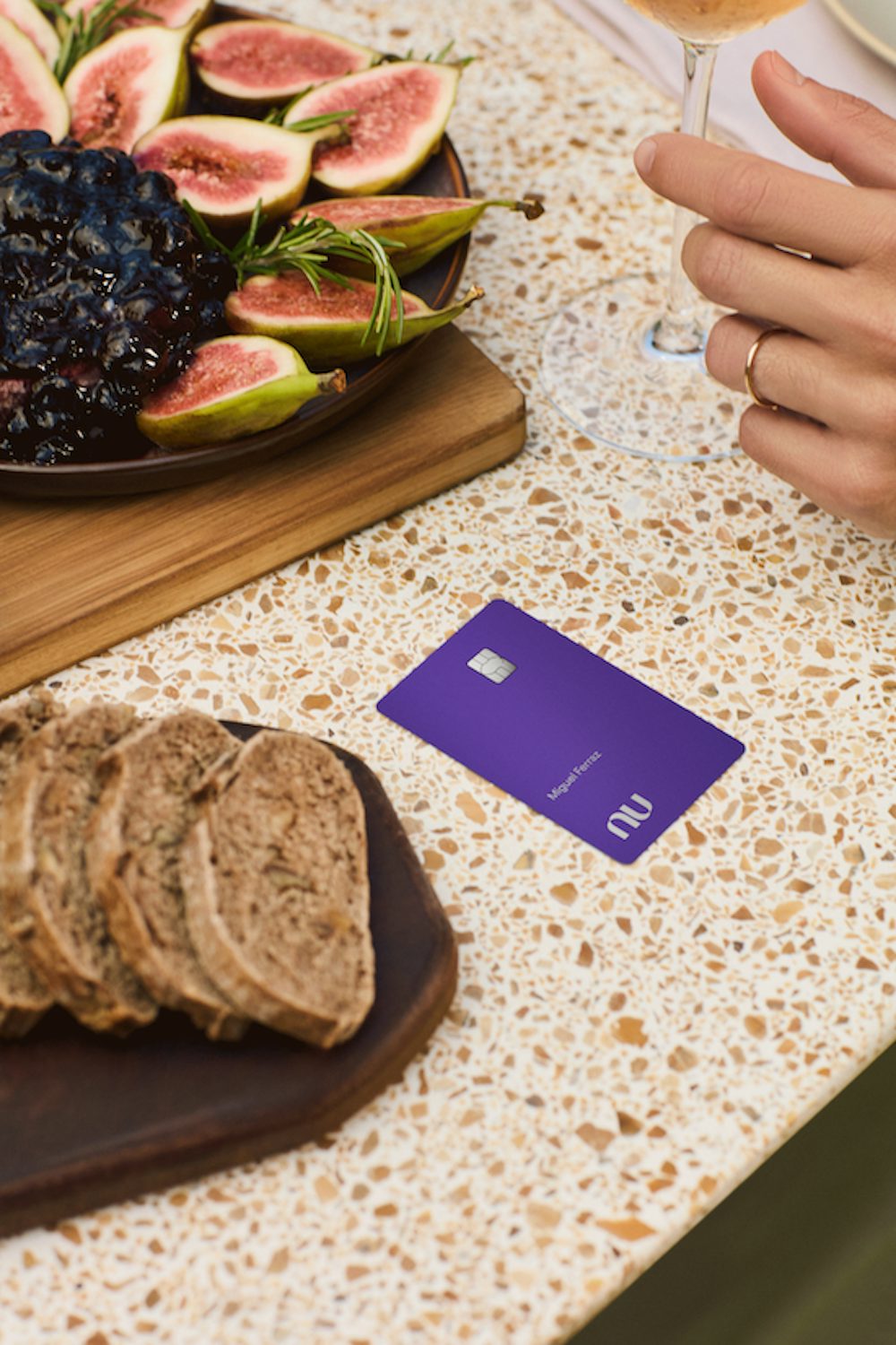 Cartão Ultravioleta em cima de um balcão, ao lado de uma tábua com figos cortados e outra com pães fatiados.
