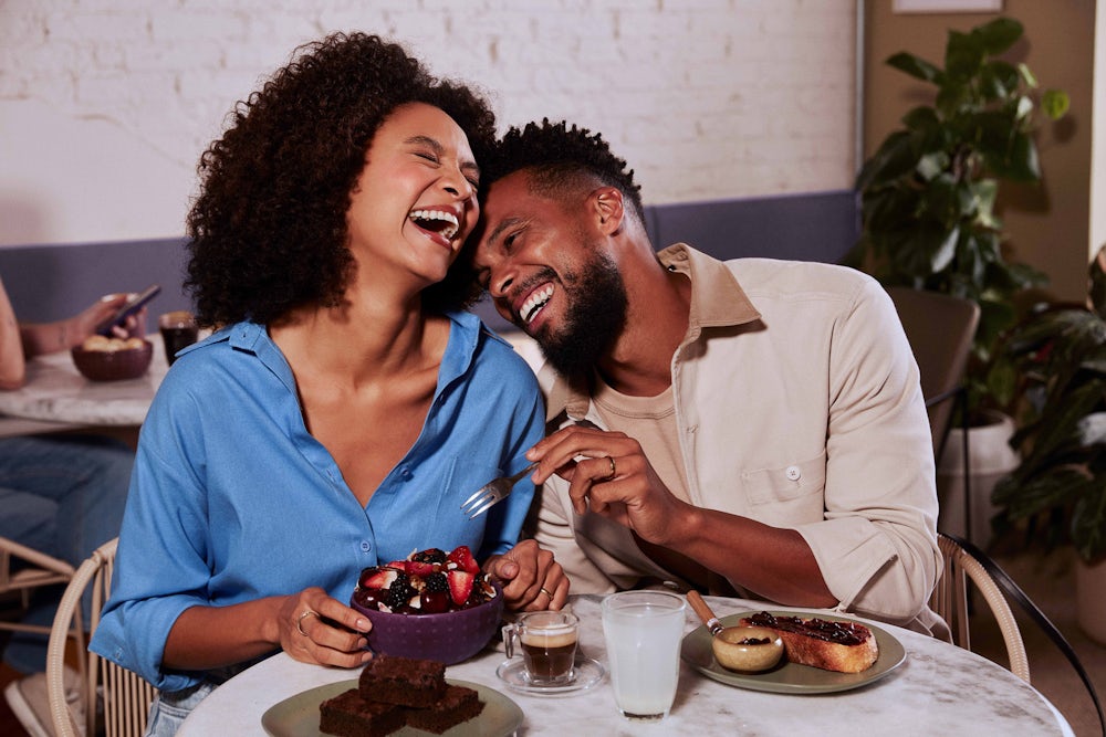 Homem e mulher sentados à mesa sorrindo