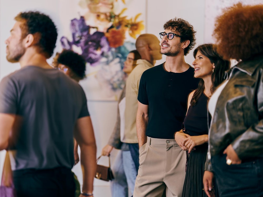 Pessoas observando obras de arte em uma exposição.