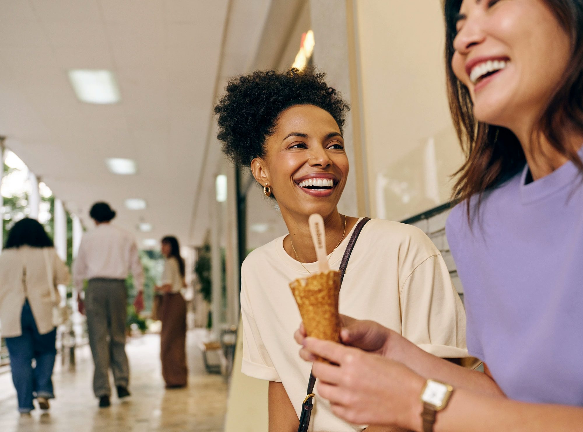 Duas mulheres rindo juntas enquanto uma delas segura um sorvete