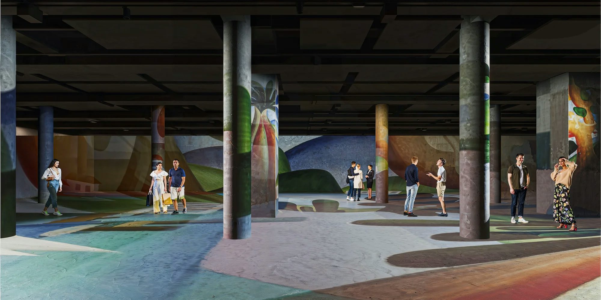 Salão sustentado por colunas de concreto cilíndricas, onde o piso e os fundos são inteiramente cobertos por uma projeção contínua de pinturas artísticas coloridas e paisagens estilizadas.