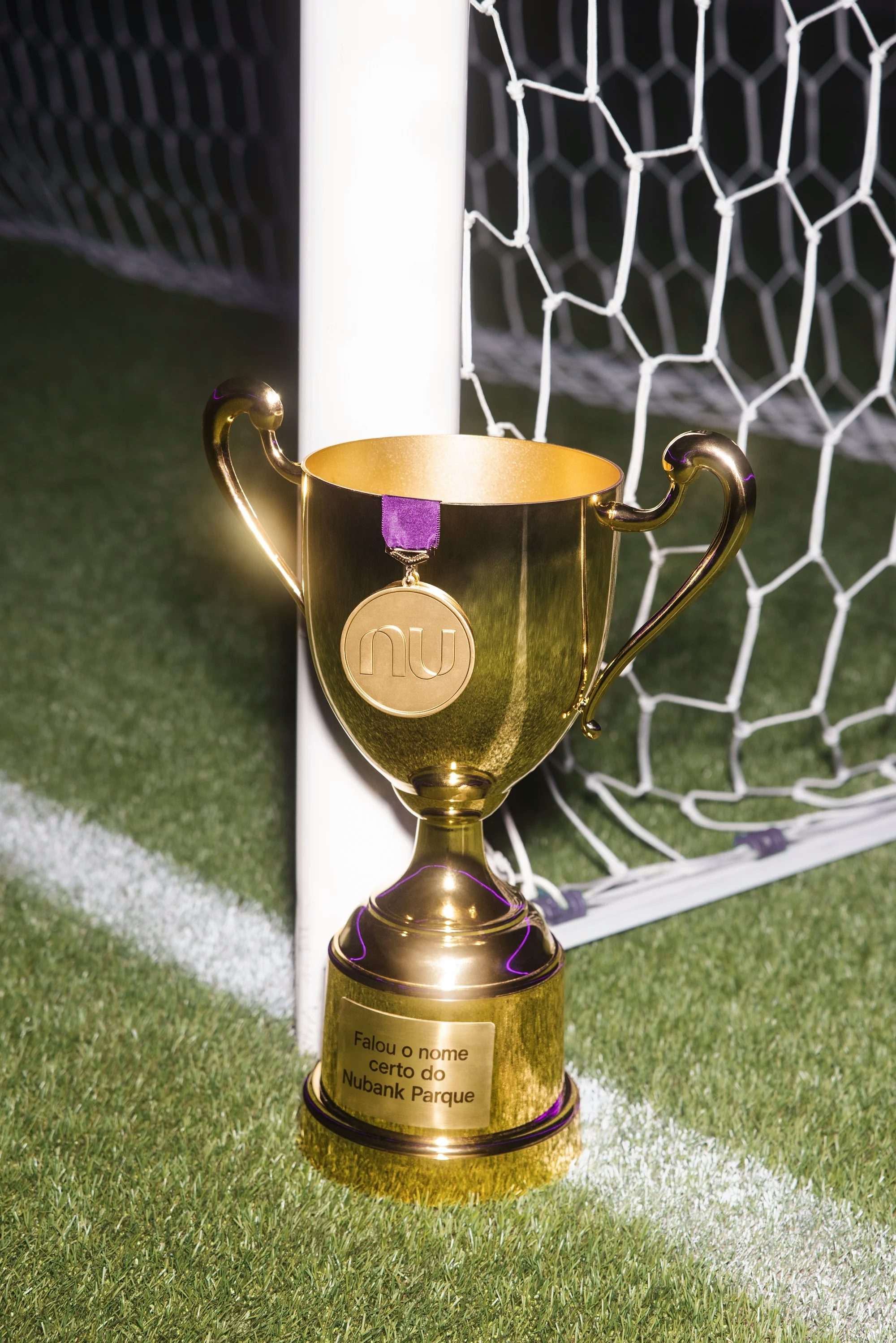 Troféu posicionado no gramado perto da trave