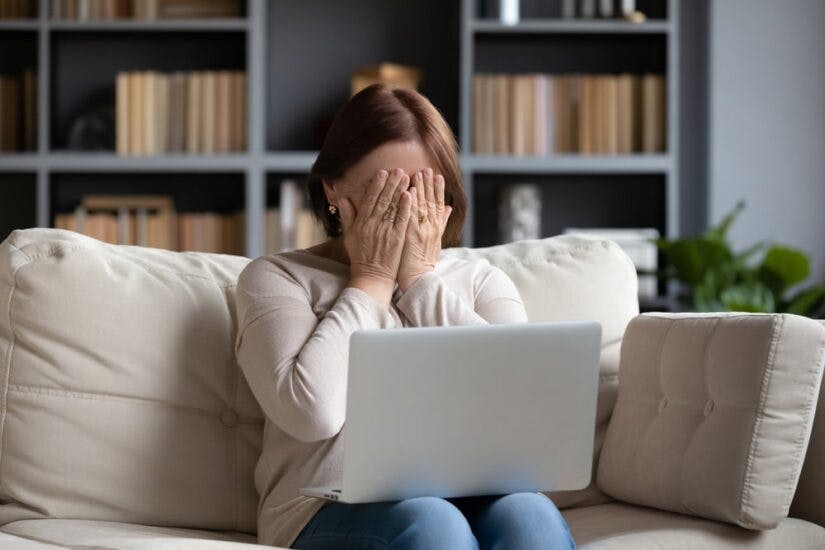 Woman Covering Her Face With A Laptop On Her Lap