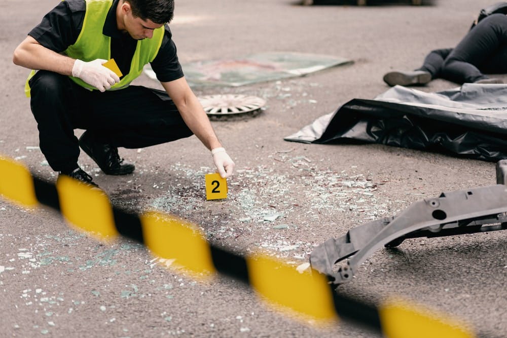 Crime Scene Investigator Looking Over Broken Glass