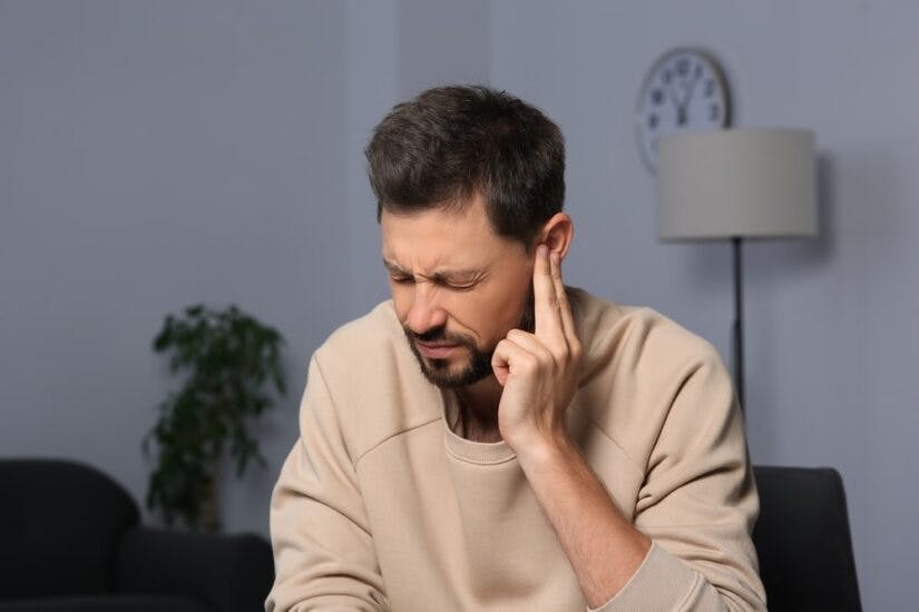 A Man Holding Fingers Up To His Ear In Pain