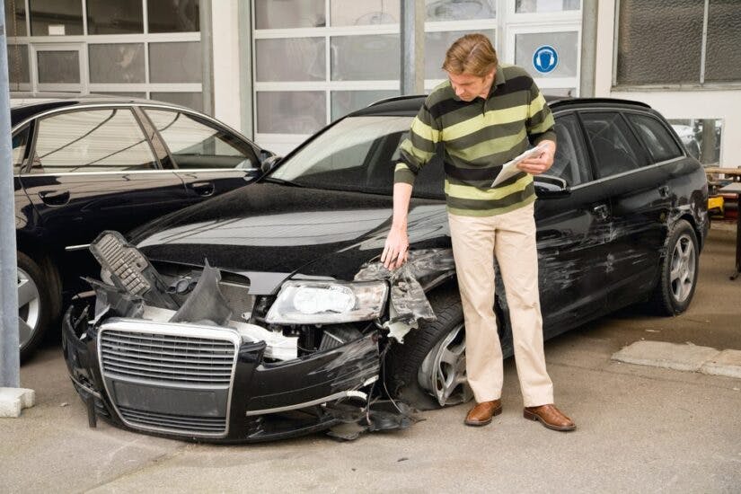 A Car Inspector Looking At A Damaged Car