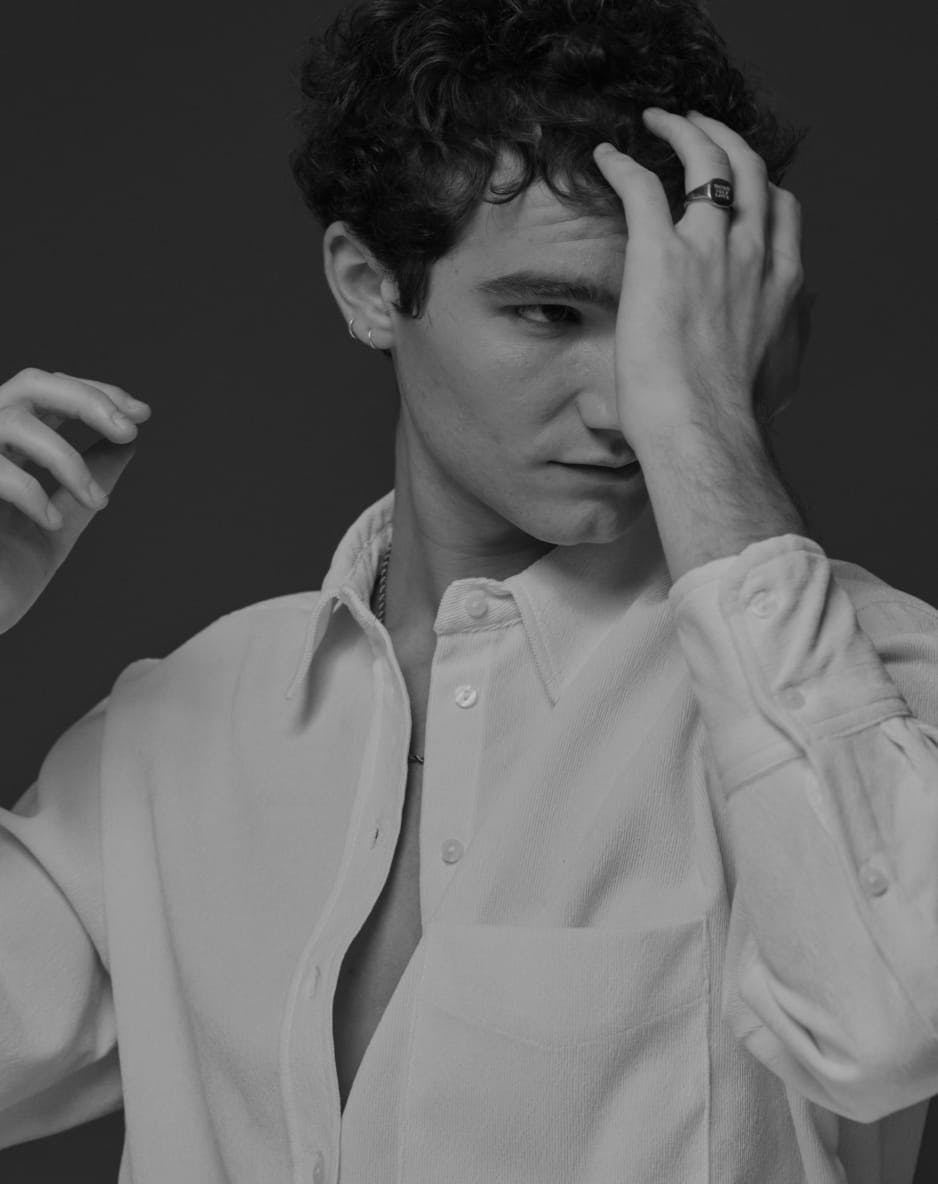 Black and white image of a man with a hand to his hair