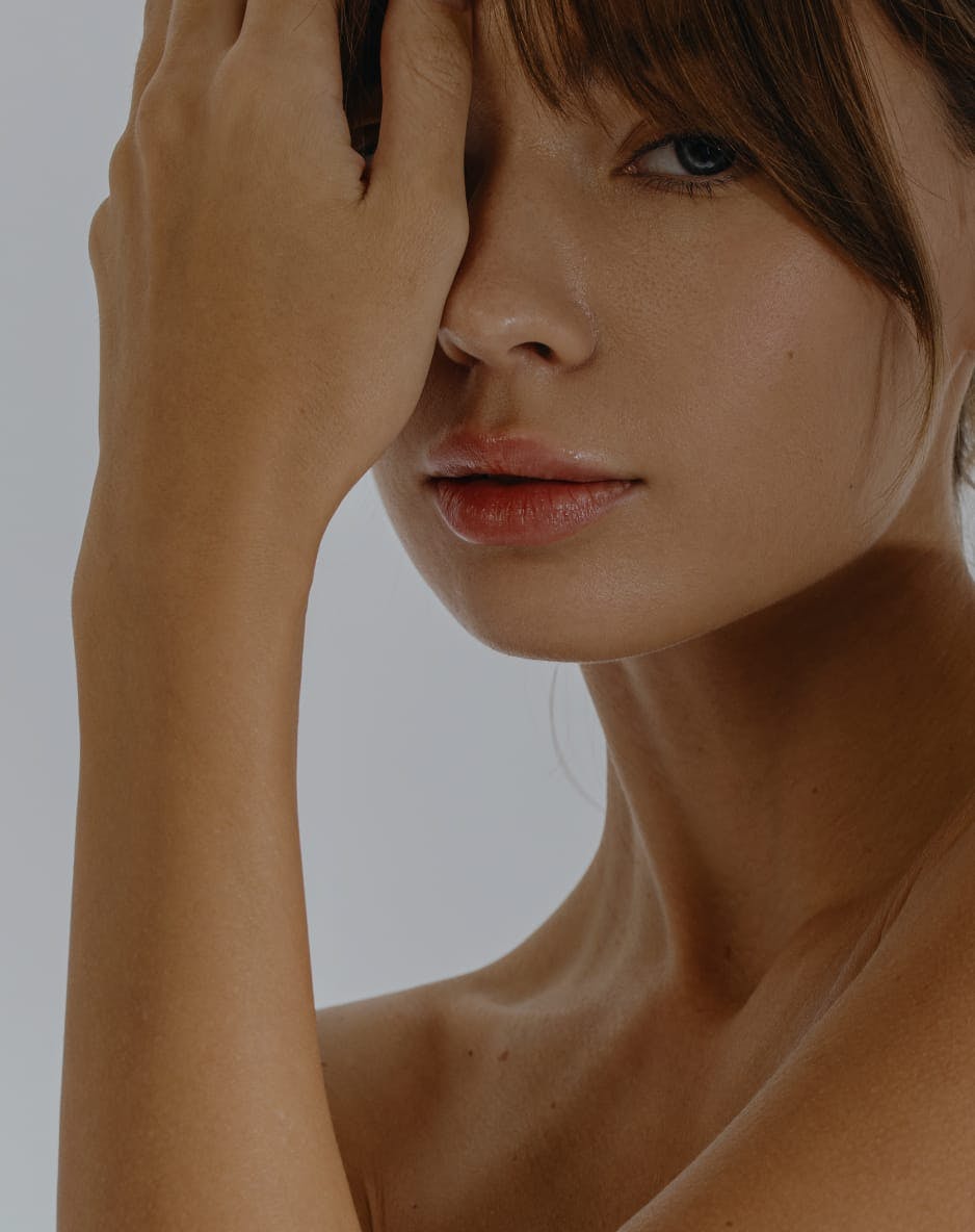 Close-up of a woman’s face, with her hand covering one eye