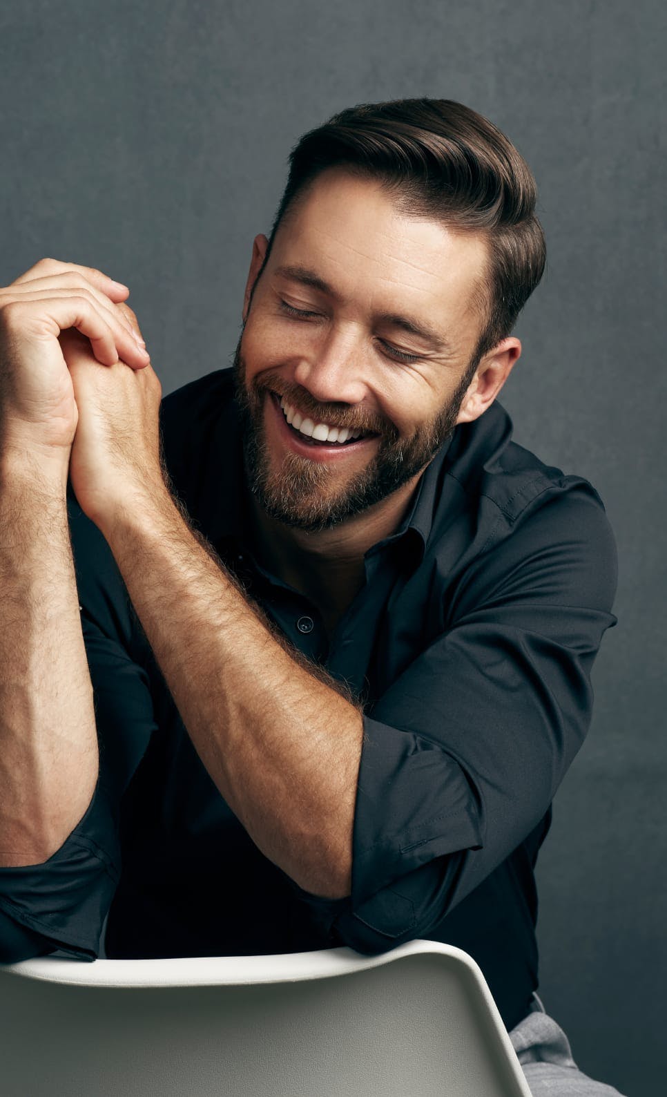 Man sitting in a chair backwards and smiling with his eyes closed