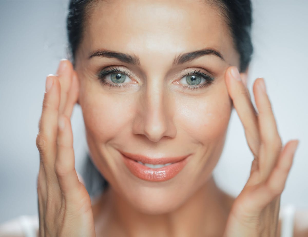close up of woman's face with her hands on her temples
