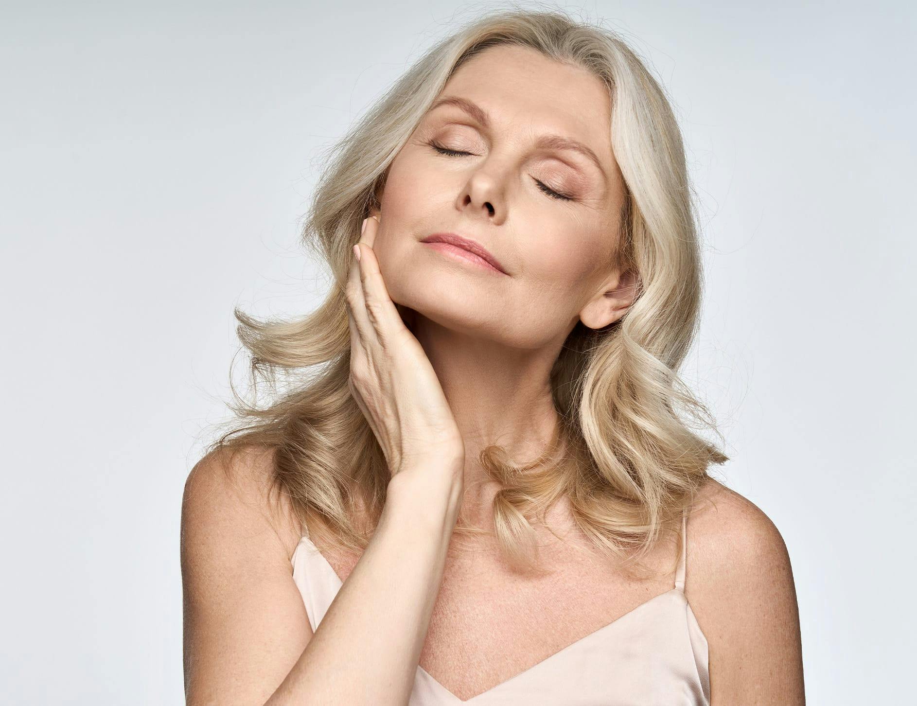 older woman touching her jaw with her eyes closed