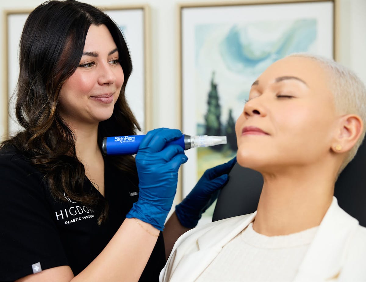 nurse holding microneedling machine near patient's face
