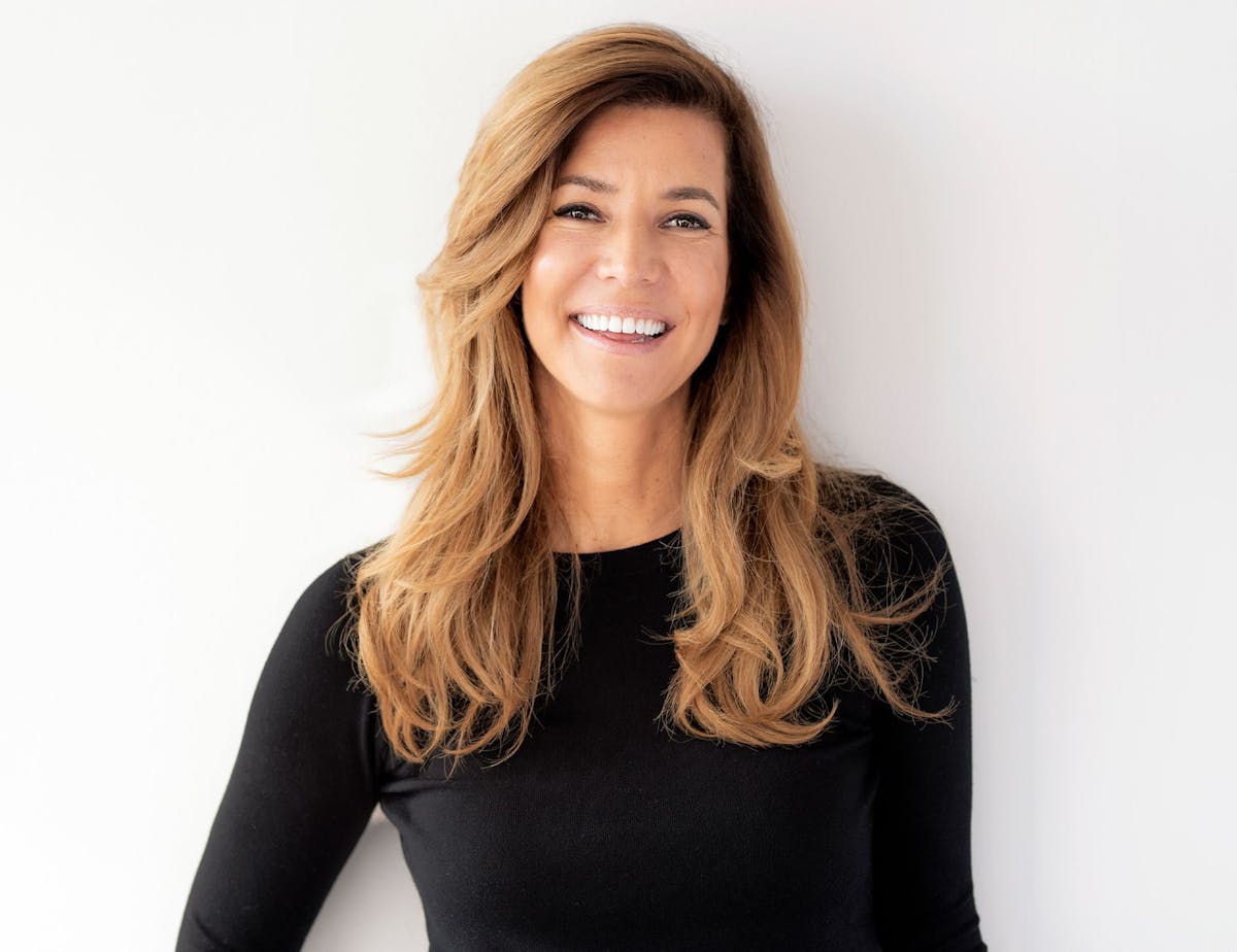woman with caramel hair in black shirt smiling forward