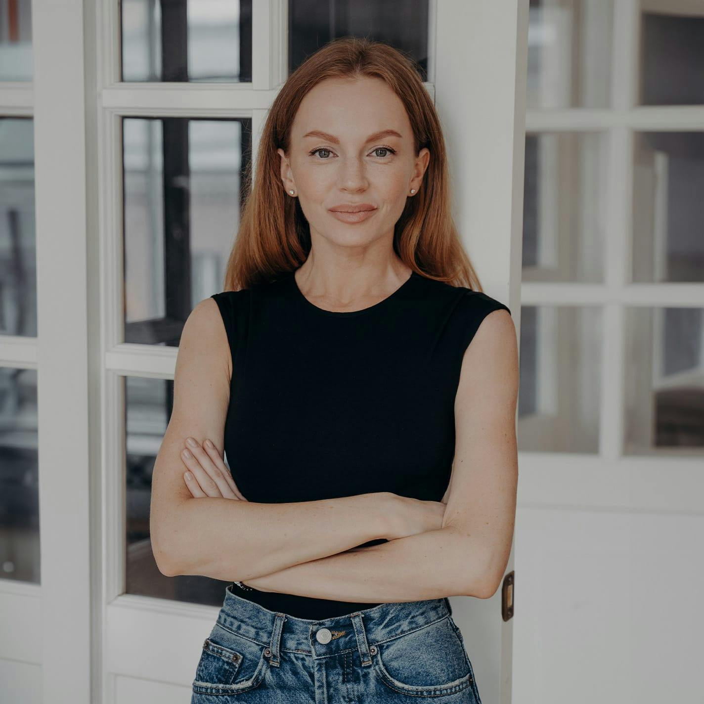 woman crossing her arms standing in front of windows