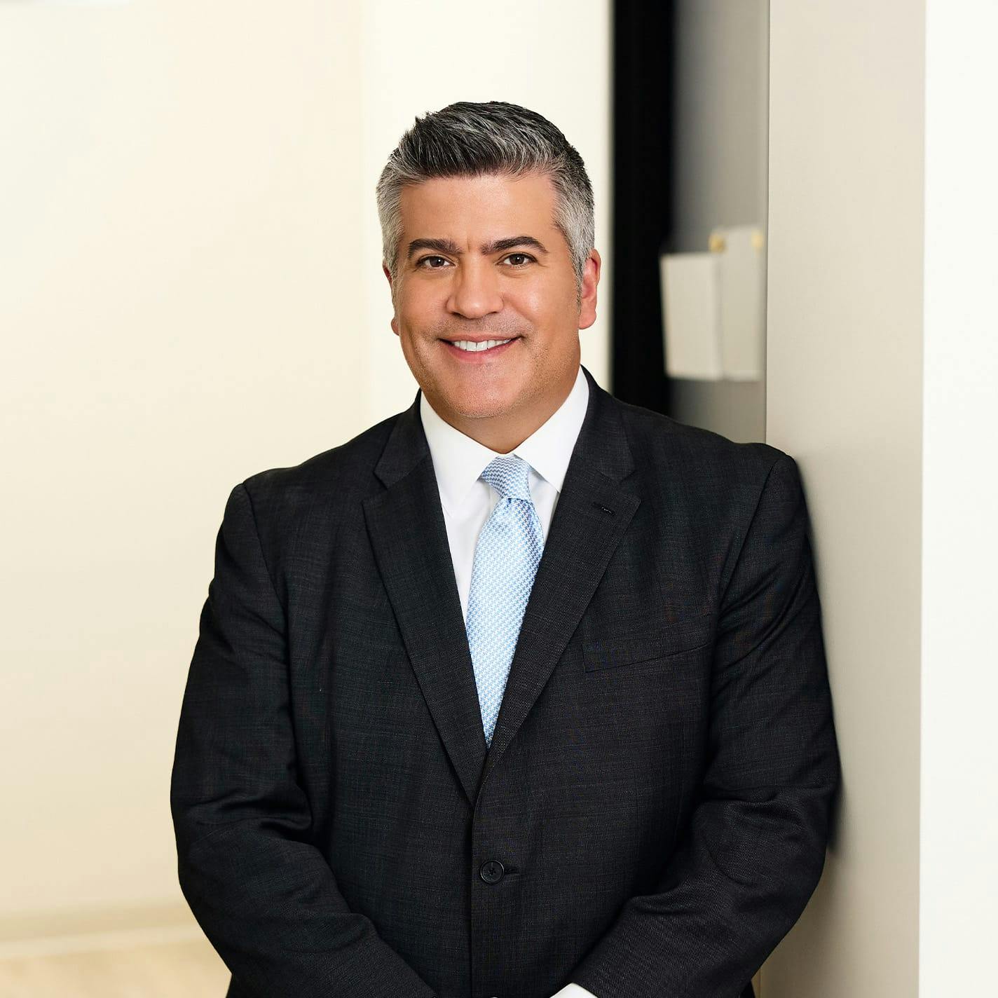 Dr. Higdon in suit leaning against wall