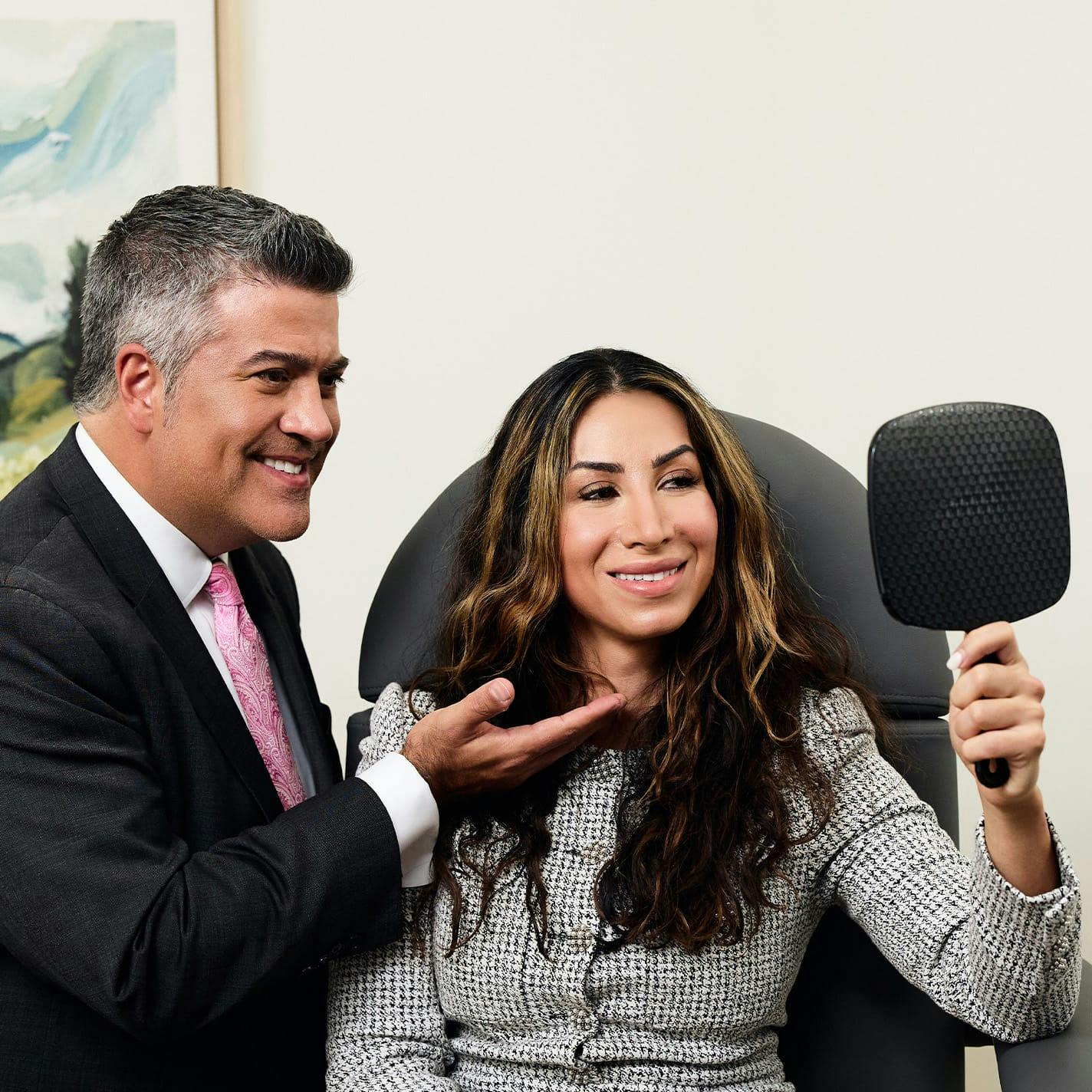 Dr. Higdon with patient sitting in chair as they both look into handheld mirror
