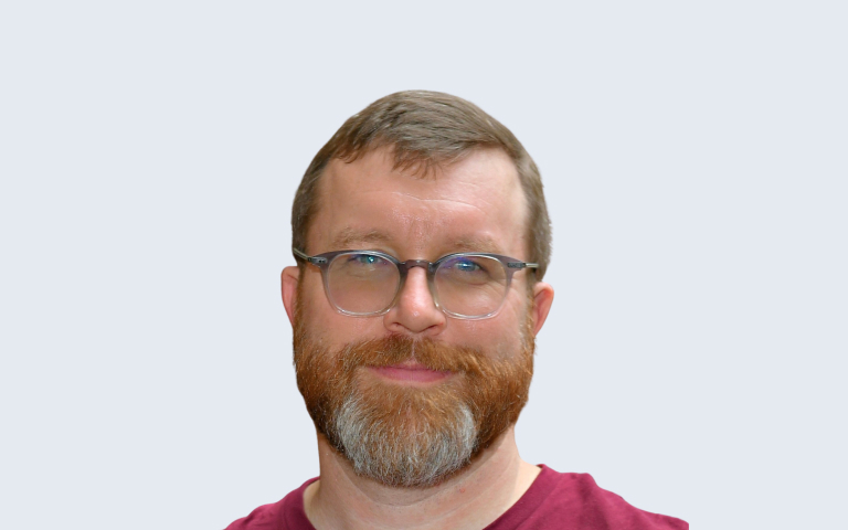 headshot of man with short hair and a trimmed ginger beard wearing glasses