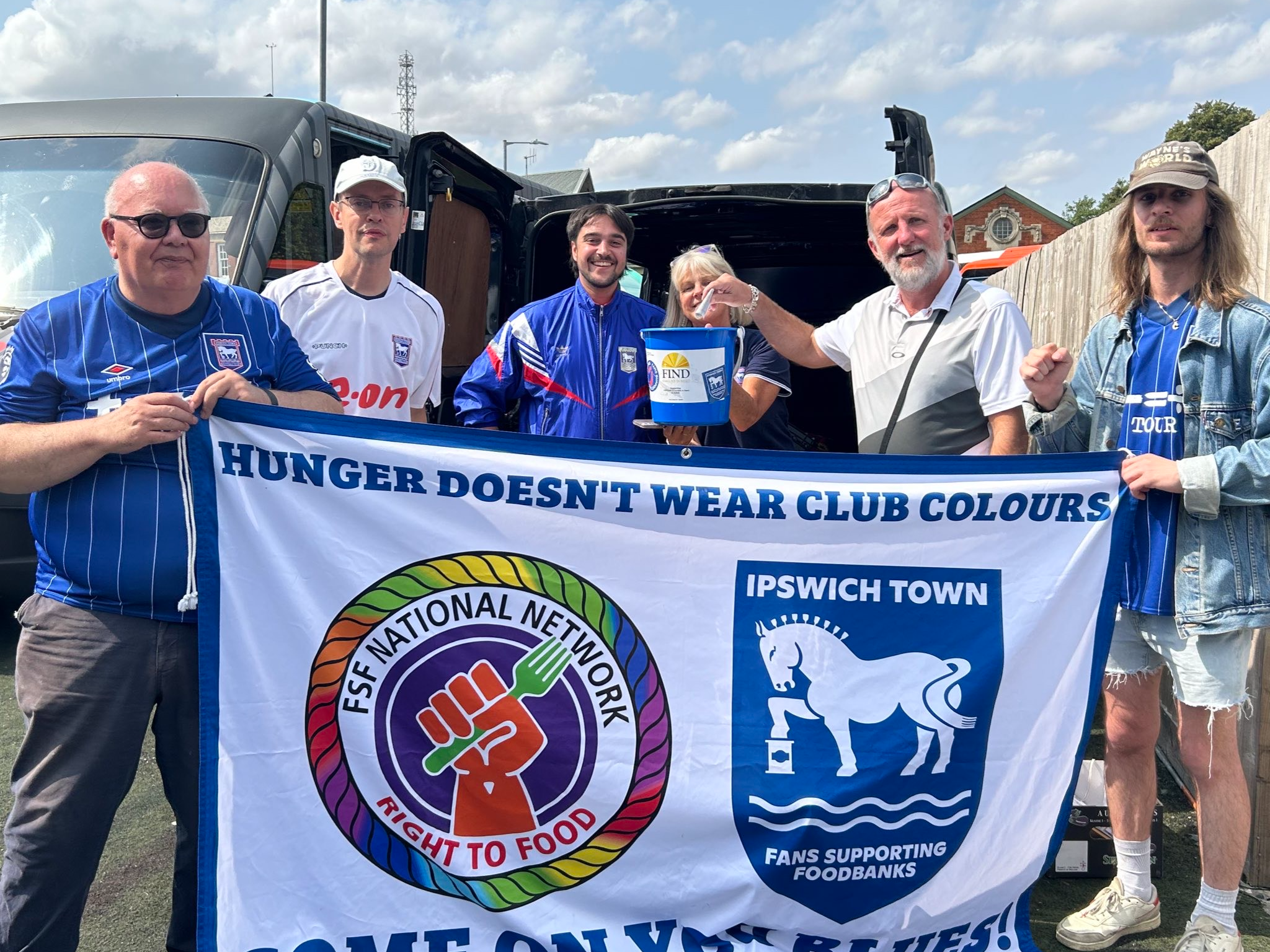 Ipswich Town Fans Supporting Foodbanks holding a sign and donations bucket