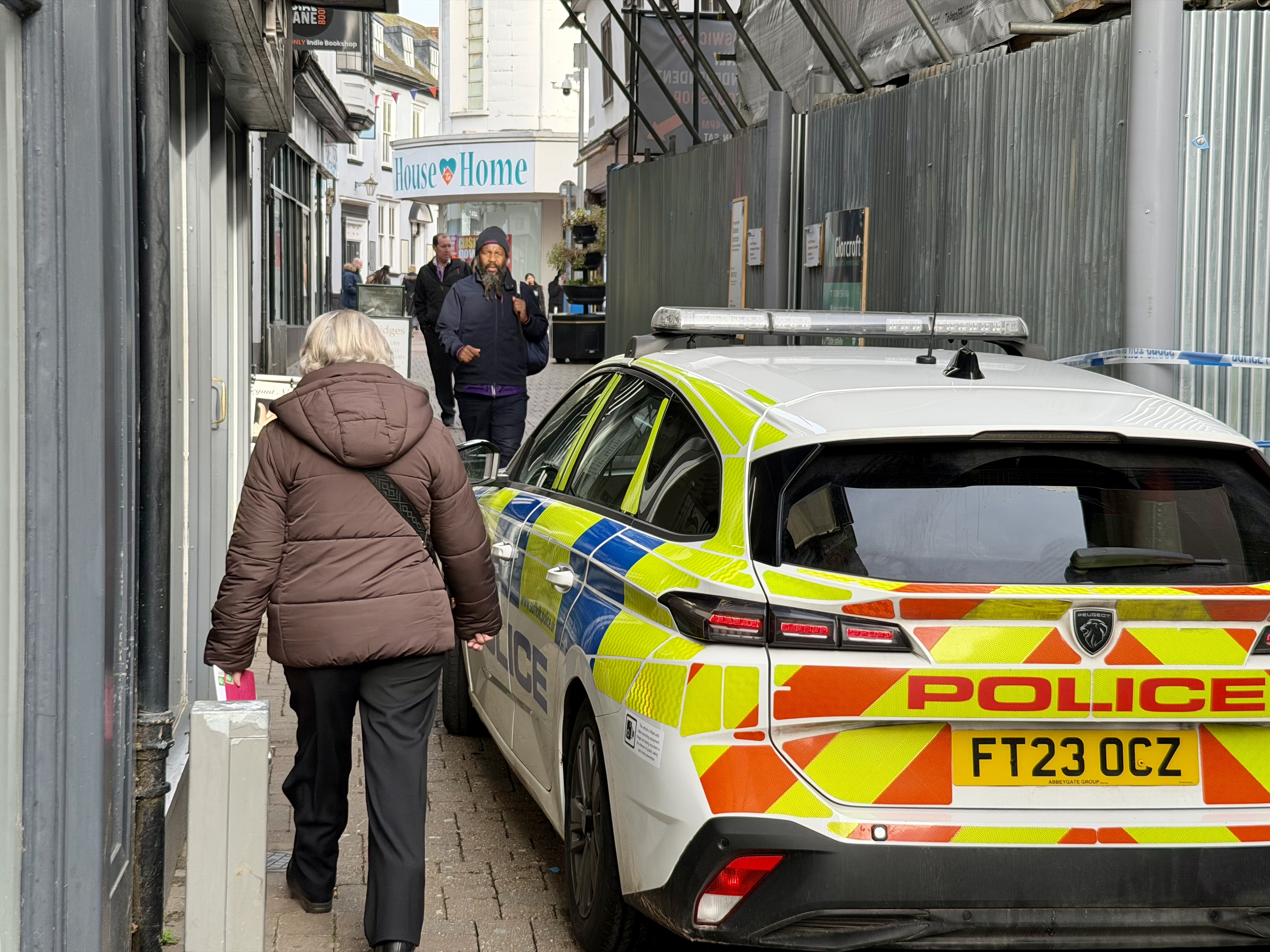 Pedestrians walk past the scene where police remain present