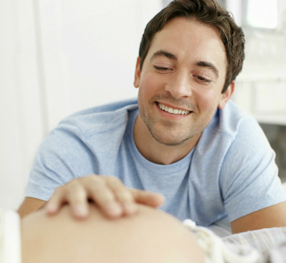 Mann streichelt den Babybauch seiner Frau
