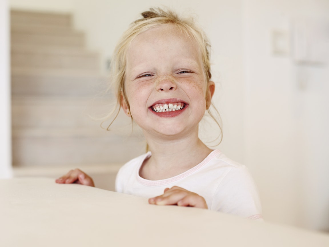 Junges Mädchen zeigt lachend ihre Zähne